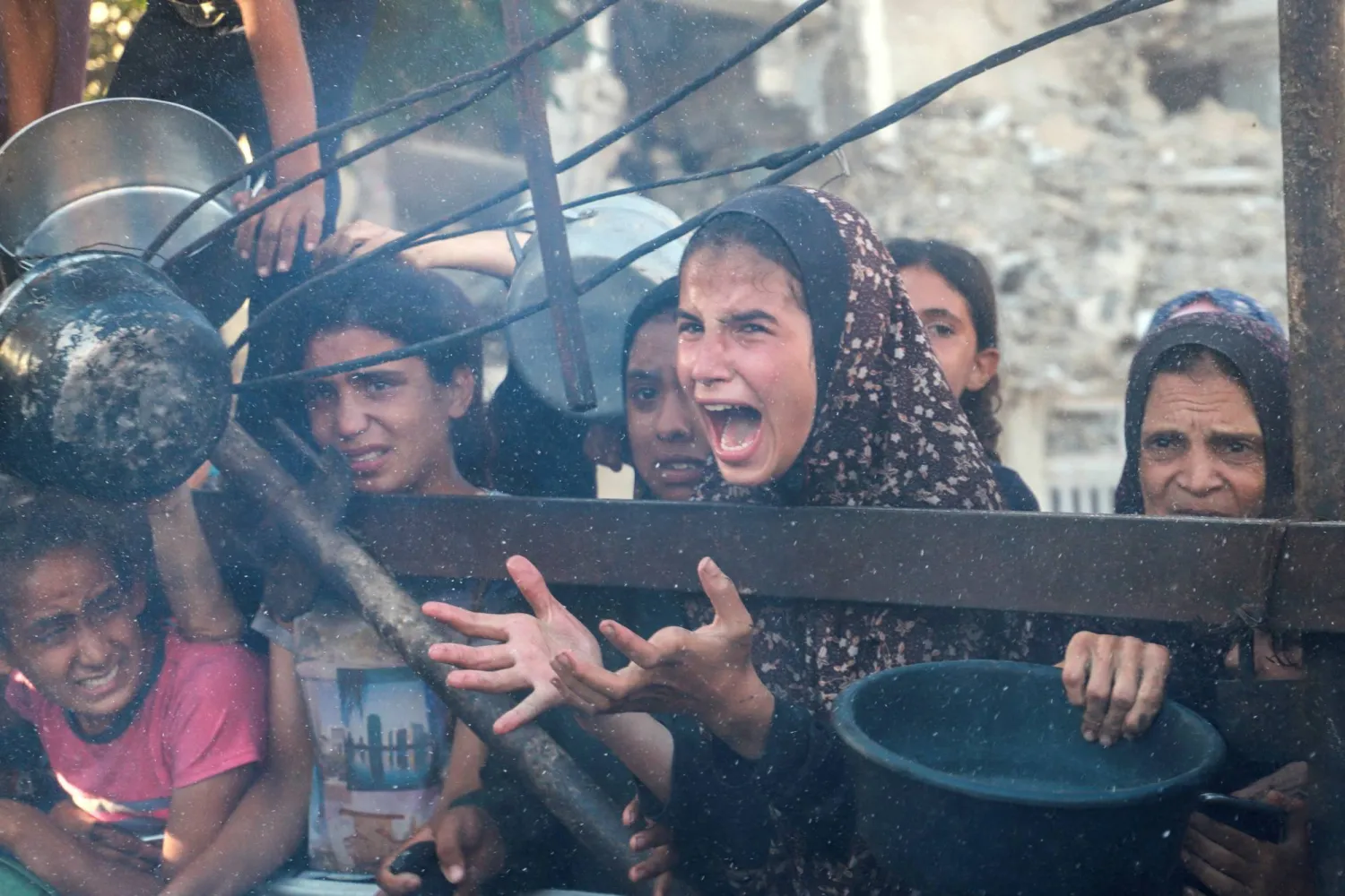 فتاة فلسطينية تتفاعل بينما تنتظر توزيع الطعام من مطبخ خيري وسط أزمة الجوع في مدينة غزة (رويترز)