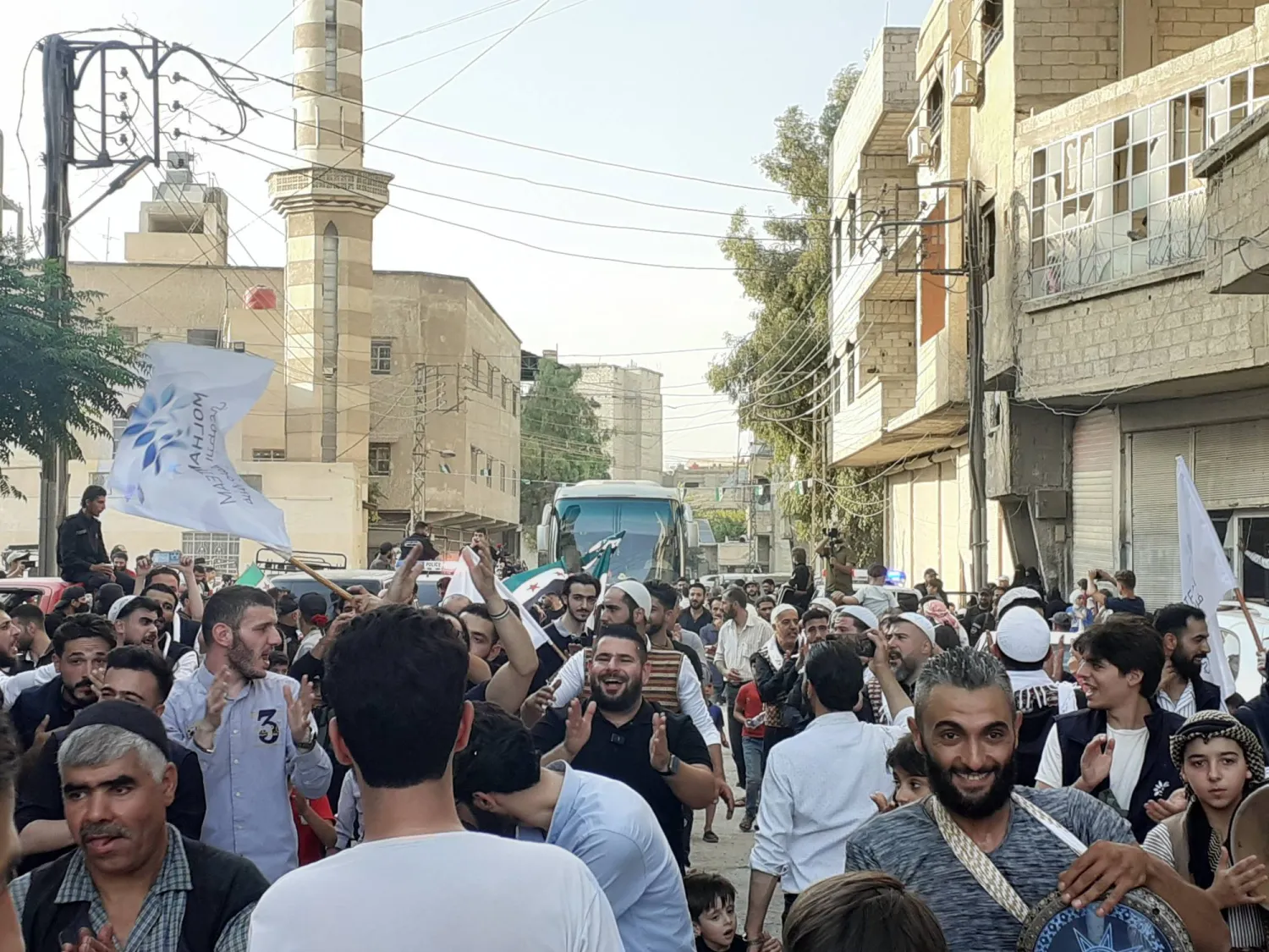 حشد المستقبِلين يحيط بحافلة تُقل عائدين في بلدة جسرين بغوطة دمشق الشرقية (الشرق الأوسط)