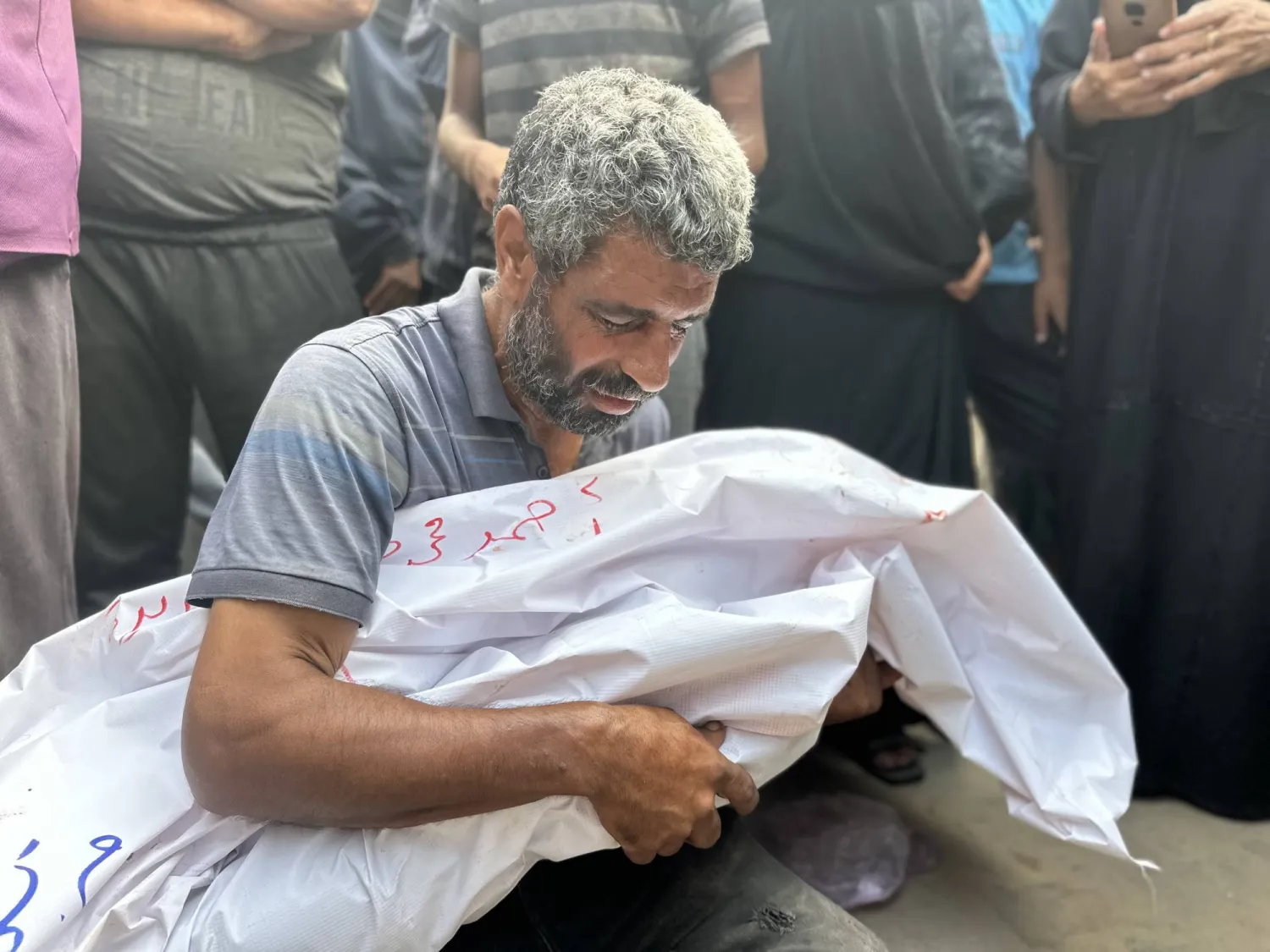 رجل يبكي على أحد أقاربه مع وصول جثث فلسطينيين قُتلوا في هجوم إسرائيلي على خيام إلى مستشفى النصر في خان يونس اليوم (د.ب.أ)