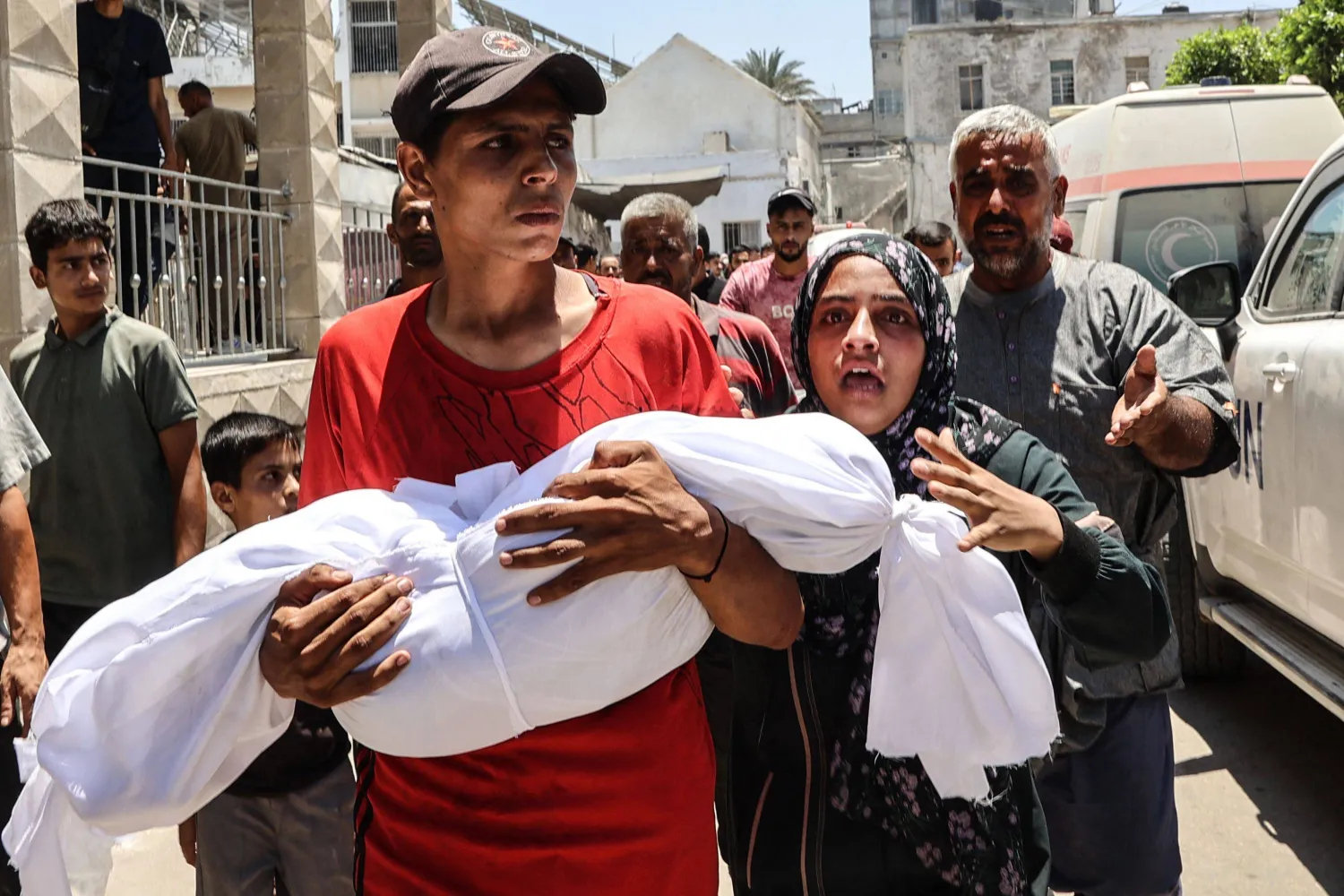 شاب يحمل جثة طفل كان ضمن ضحايا قصف إسرائيلي استهدف فلسطينيين كانوا ينتظرون أمام نقطة لتوزيع الماء في مدينة غزة أمس (أ.ف.ب) 