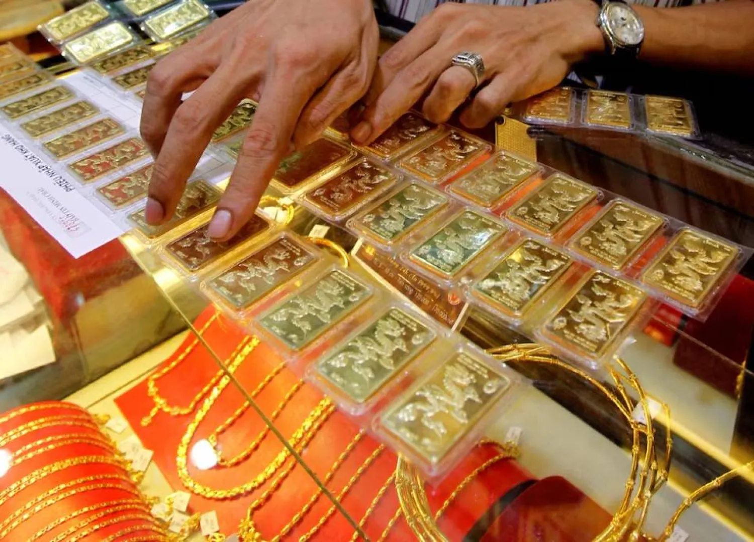 موظف يفحص سبائك ذهبية قبل بيعها لزبون بمتجر في هانوي (رويترز)