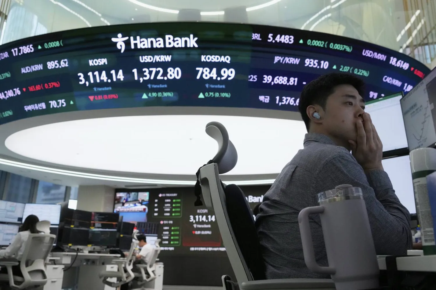 متداول عملات يتابع شاشة تعرض مؤشر «كوسبي» وسعر صرف الدولار مقابل الوون في بنك «هانا» بسيول (أ.ب)