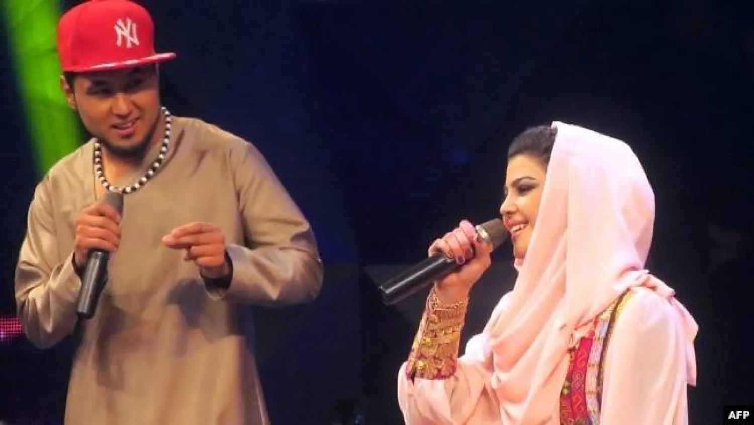 المغنية الأفغانية زلالة هاشمي (يمين) تؤدي أغنية إلى جانب منافسها سيد جمال مبارز (يسار) خلال مسابقة الموسيقى التلفزيونية «النجم الأفغاني» (أ.ف.ب)
