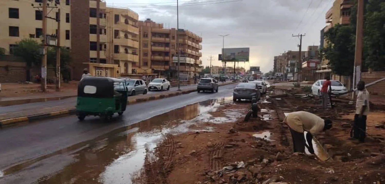 مواطن يحاول تصريف المياه من أمام مسكنه في مدينة أم درمان (الشرق الأوسط)