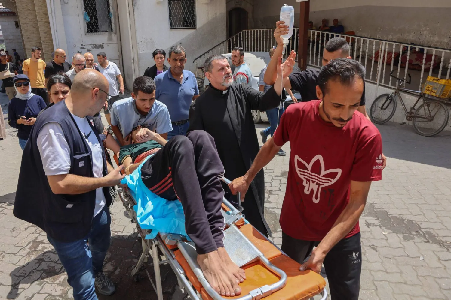 فلسطينيون ينقلون جريحاً أُصيب في غارة إسرائيلية على كنيسة العائلة المقدسة بغزة اليوم (أ.ف.ب)