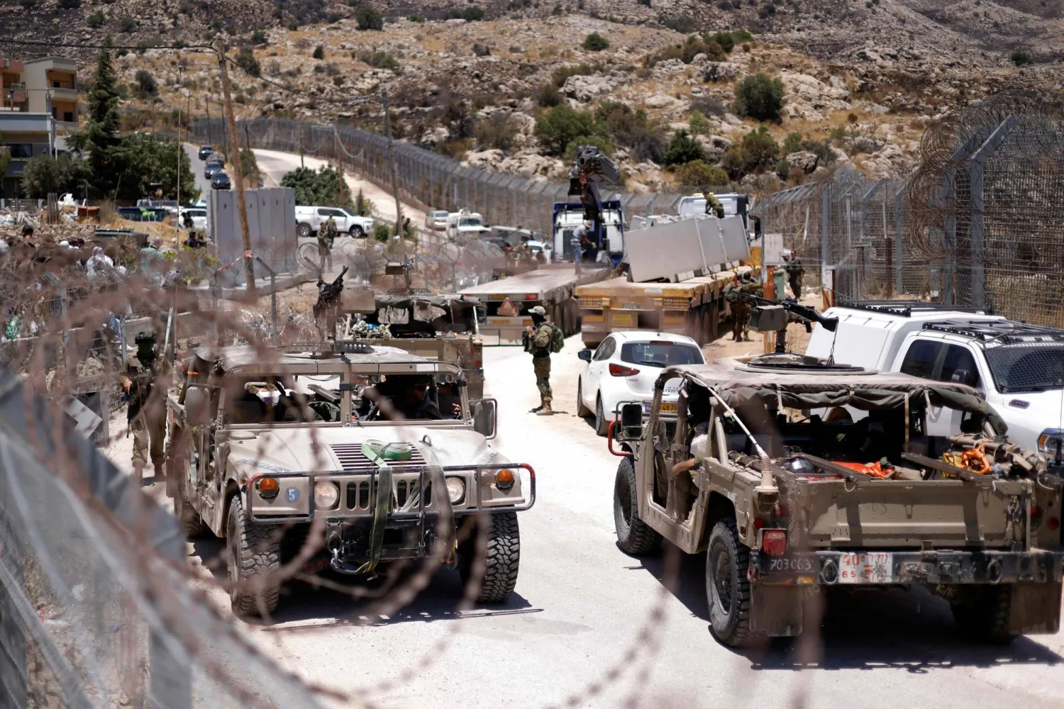 مركبات عسكرية إسرائيلية تسير إلى جانب السياج الحدودي قرب قرية مجدل شمس بمرتفعات الجولان المحتلة يوم الخميس (أ.ف.ب)