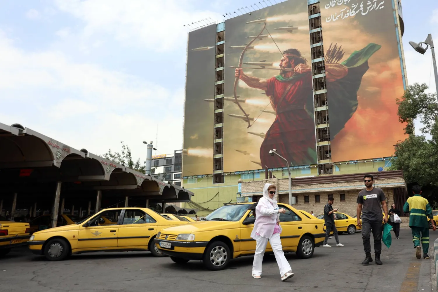 إيرانيون يسيرون قرب جدارية دعائية في طهران تستلهم شخصية من الأساطير الفارسية وهي تطلق صواريخ الأربعاء (إ.ب.أ)