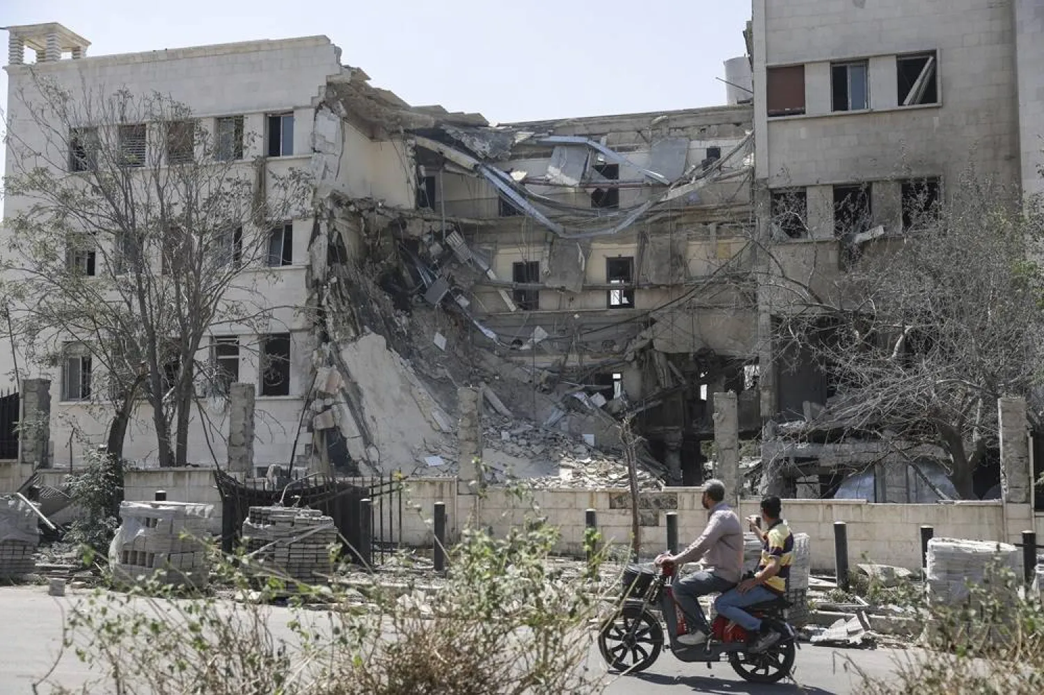 People pass in front the Syrian Defense Ministry building which on Wednesday was heavily damaged by Israeli airstrikes in Damascus, Syria, Thursday, July 17, 2025. (AP) 