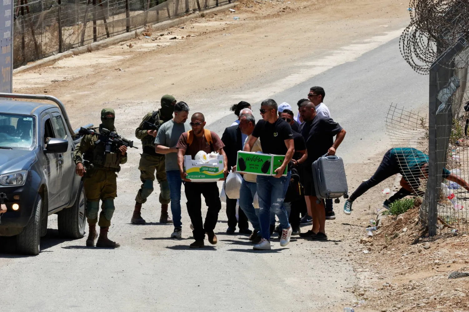 جنود إسرائيليون يرافقون مواطنين سوريين أثناء عودتهم سيراً على الأقدام من مجدل شمس إلى الداخل السوري على طول خط وقف إطلاق النار بين مرتفعات الجولان المحتلة... يوم 17 يوليو 2025 (رويترز)