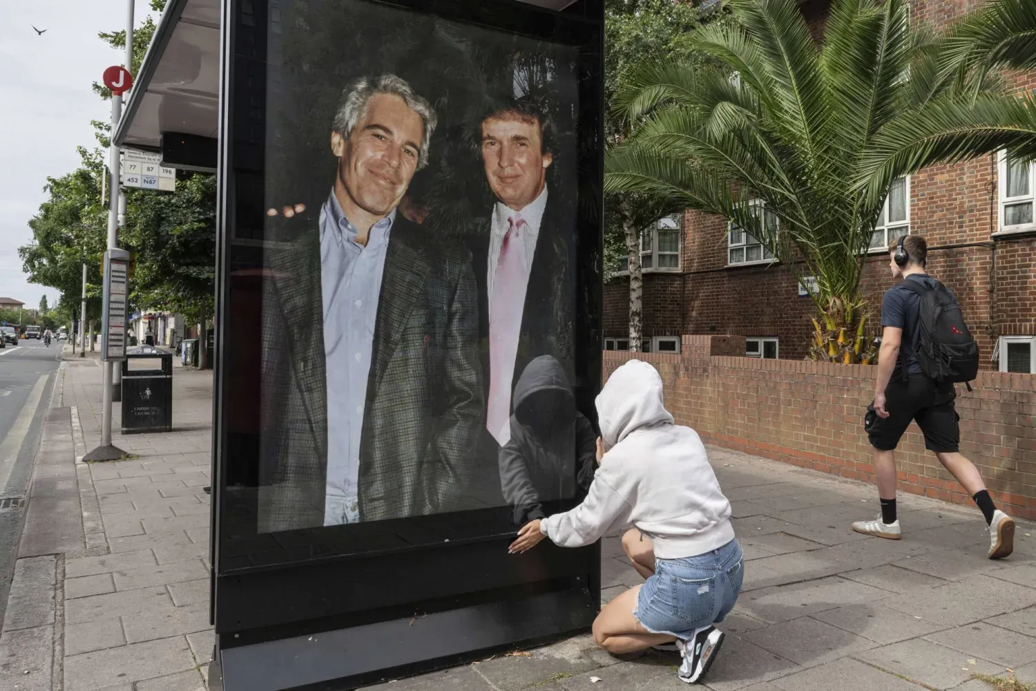 Aktivistler, Londra'daki ABD Büyükelçiliği yakınlarında Trump ve Epstein'ın resminin yer aldığı bir afiş asıyor (AP)