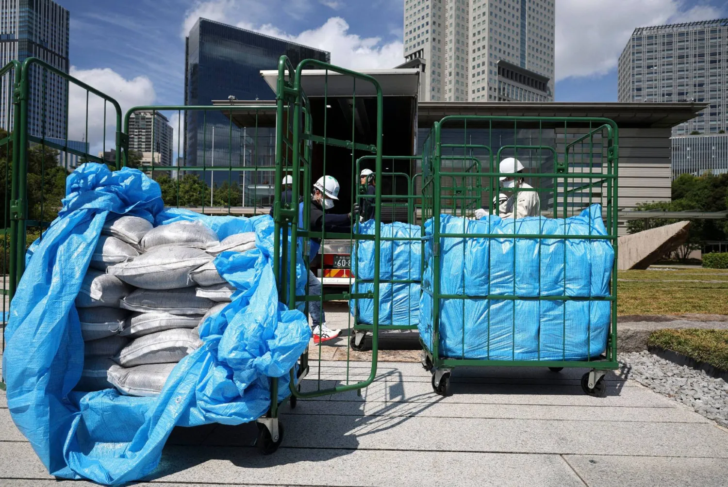 Workers unload bags of soil removed during decontamination following the Fukushima Daiichi nuclear power plant accident, at the Prime Minister's office in Tokyo on July 19, 2025. (Photo by JIJI PRESS / AFP) / Japan OUT