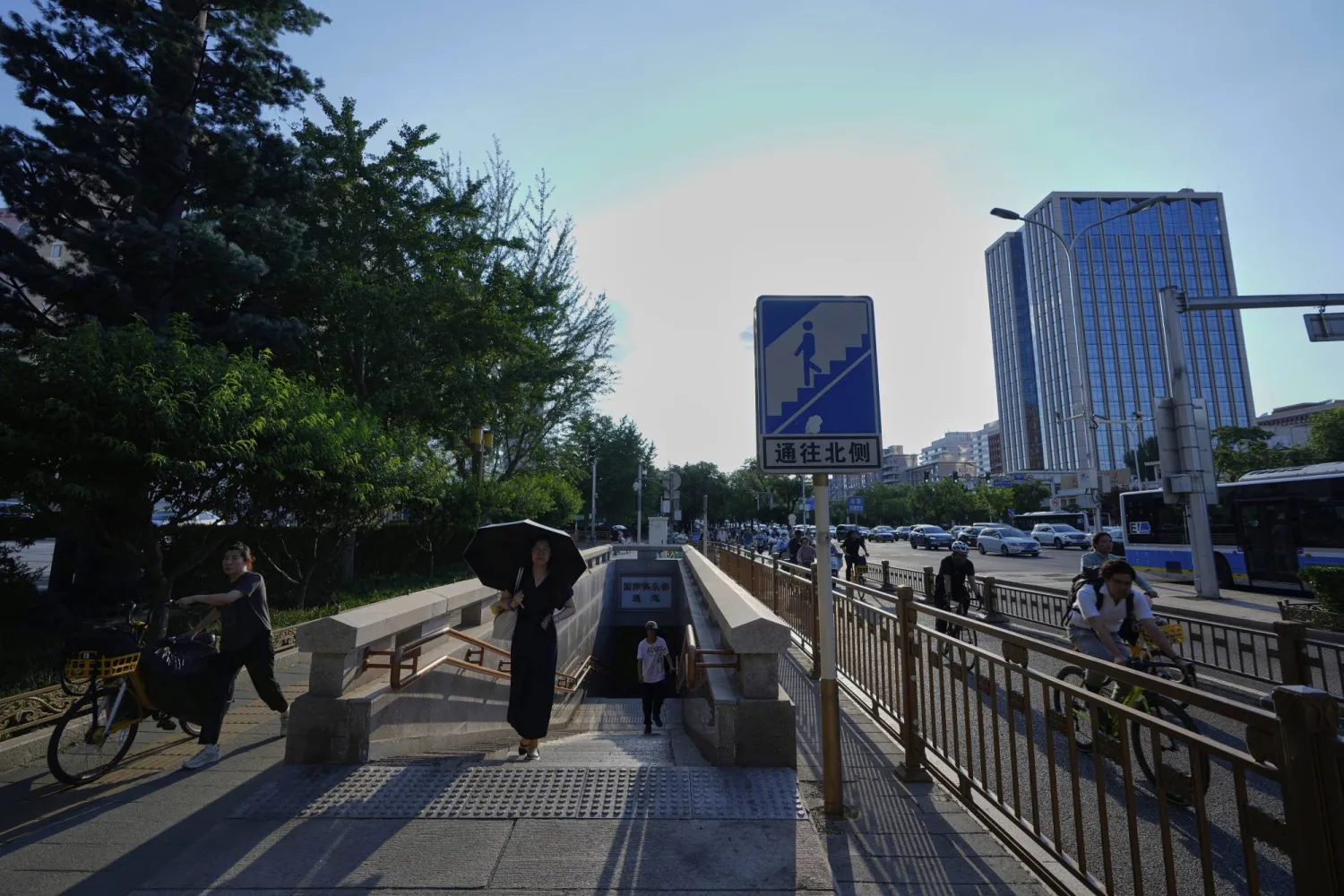 A woman holds an umbrella to shelter from the sun walks along a street in Beijing, China, Thursday, July 17, 2025. (AP Photo/Mahesh Kumar A.)