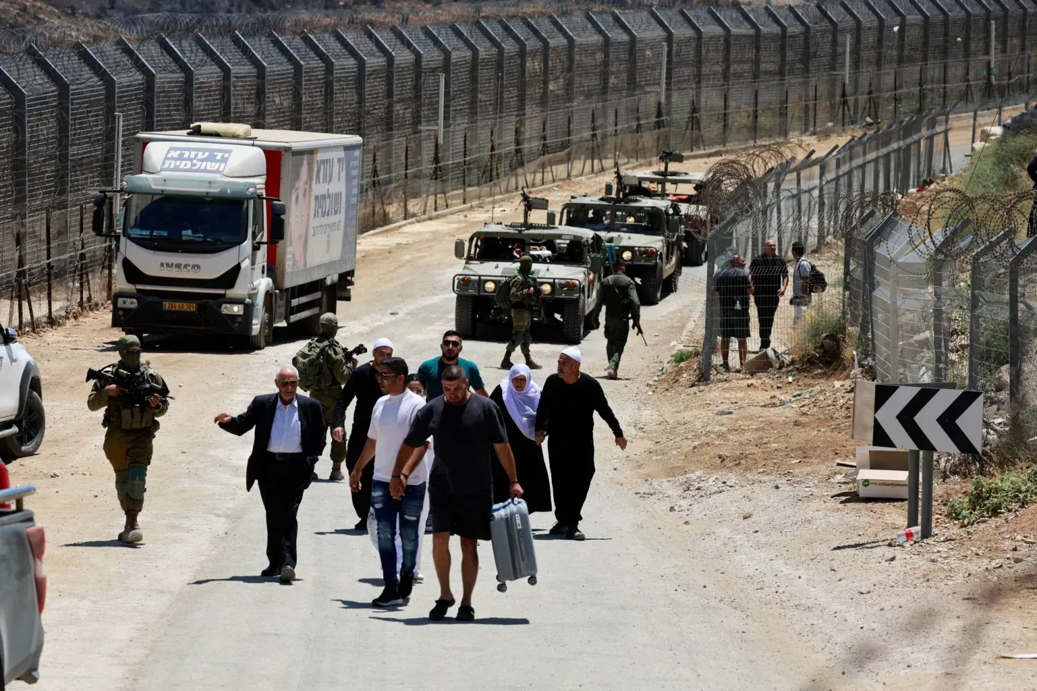 İsrail ordusu, Dürzi bölgelerinde devam eden çatışmaların ortasında Mecdel Şems'ten Suriye'ye yaya olarak dönen Suriyeli sivillere eşlik ediyor. (Reuters)