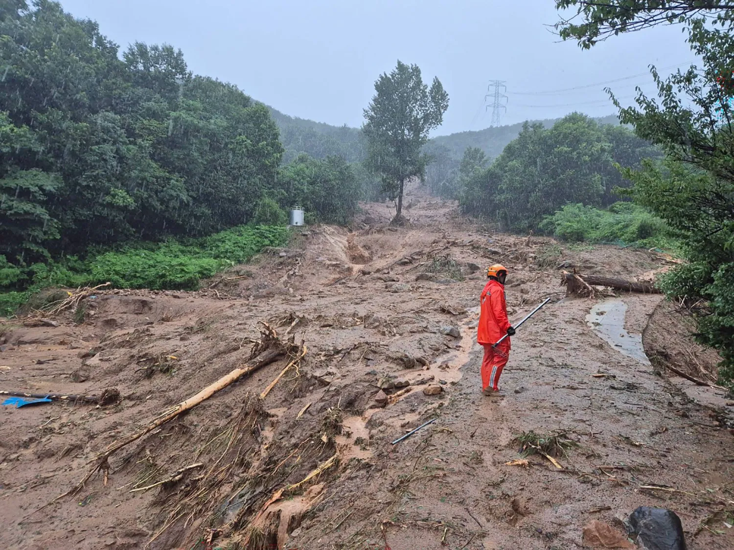 This handout photo taken on July 19, 2025 and released by Gyeongsangnam-do Fire Department via Yonhap shows a rescue member standing on a mud-covered road after a landslide hit a village in southern Sancheong county as heavy rain continued to pound the country. (Photo by Handout / Gyeongsangnam-do Fire Department / AFP) 