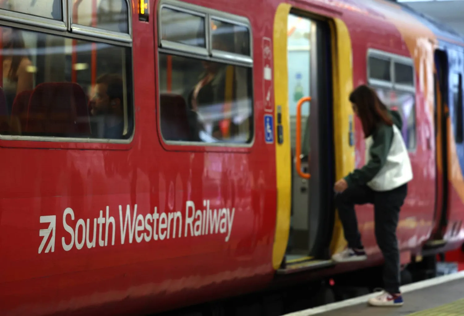 ركاب يستقلون خدمة سكة حديد «ساوث ويسترن» بإحدى محطات لندن (إ.ب.أ)