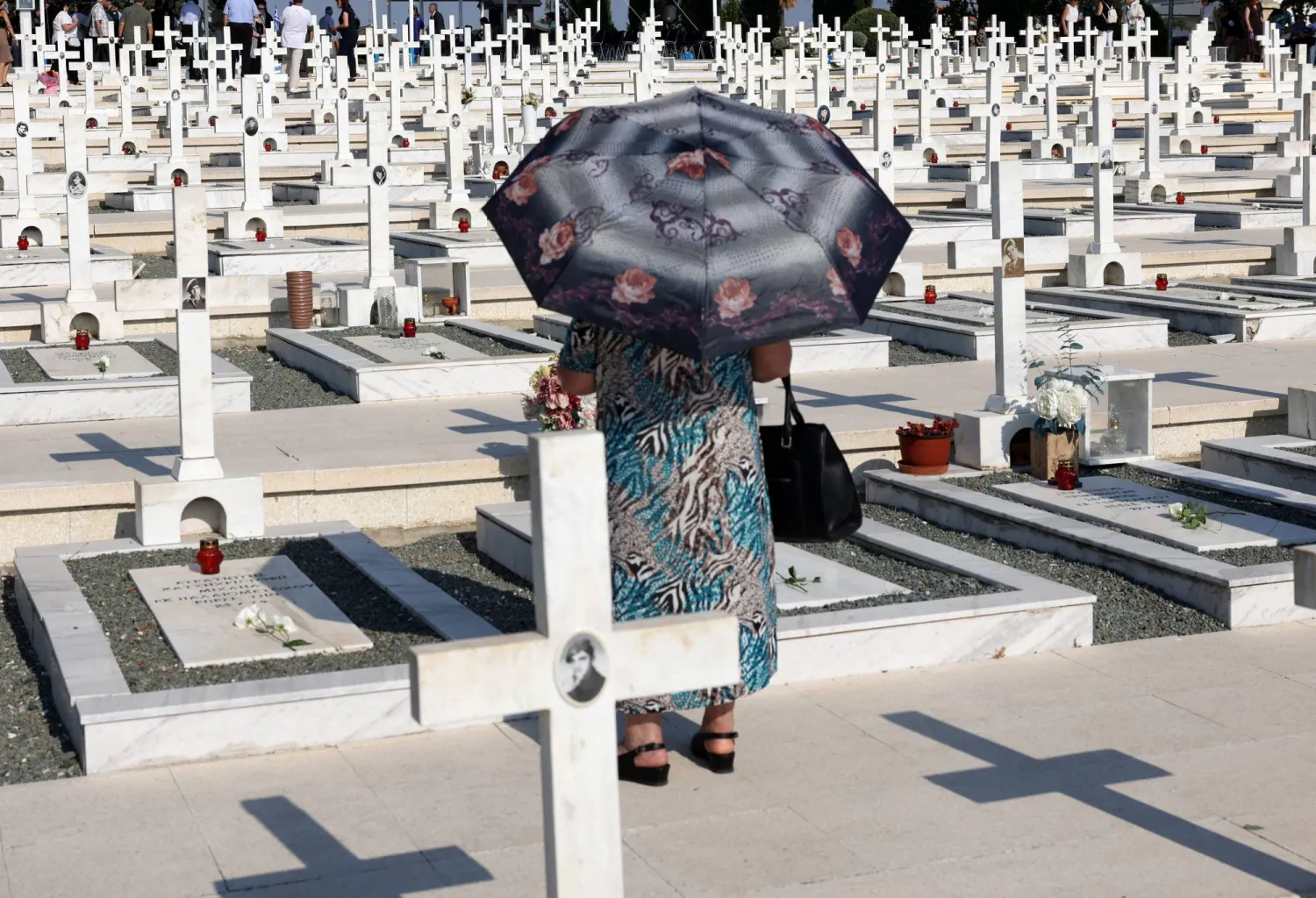 A woman walks next to the graves of soldiers killed in the 1974 Turkish invasion of Cyprus at the Tymvos Makedonitissas military cemetery in Nicosia, Cyprus July 20, 2025. REUTERS/Yiannis Kourtoglou