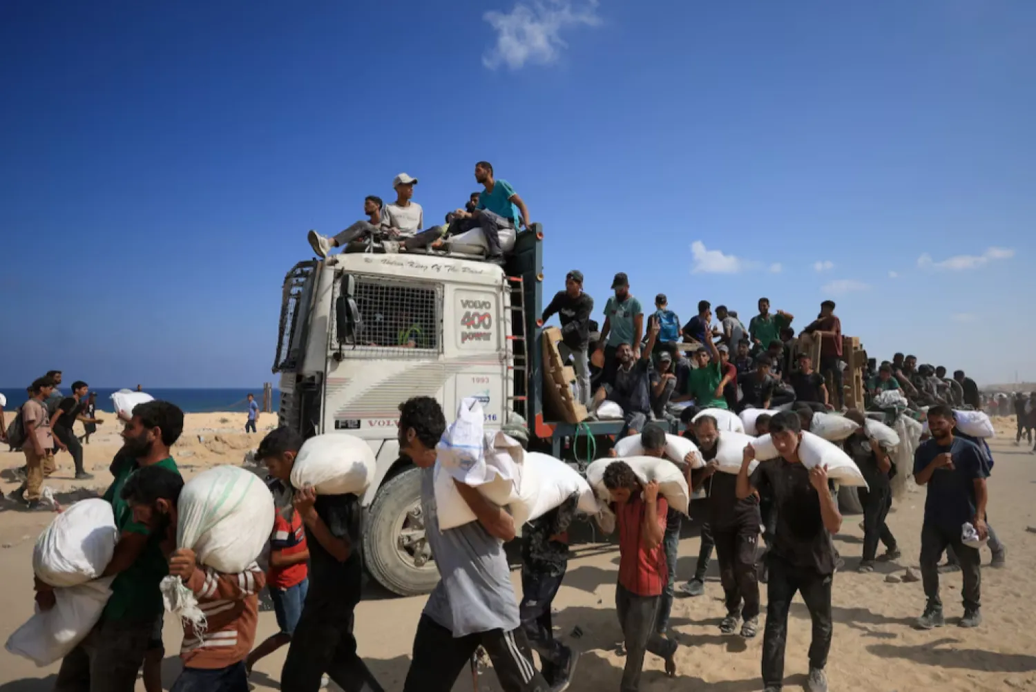 Palestinians carry aid supplies that entered Gaza through Israel, amid a hunger crisis, in Beit Lahia in the northern Gaza Strip July 20, 2025. REUTERS/Dawoud Abu Alkas