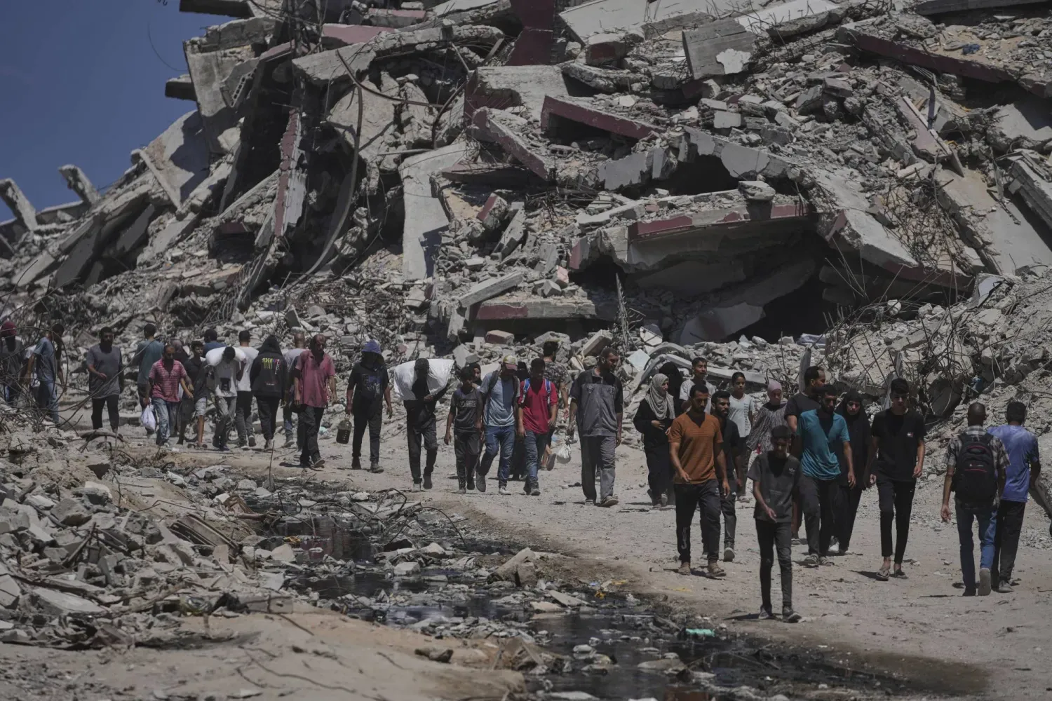 Filistinliler, Gazze Şeridi'nin kuzeyinde, Gazze şehrine giden bir kamyon konvoyundan boşalttıkları insani yardım paketlerini taşıyor (AP)