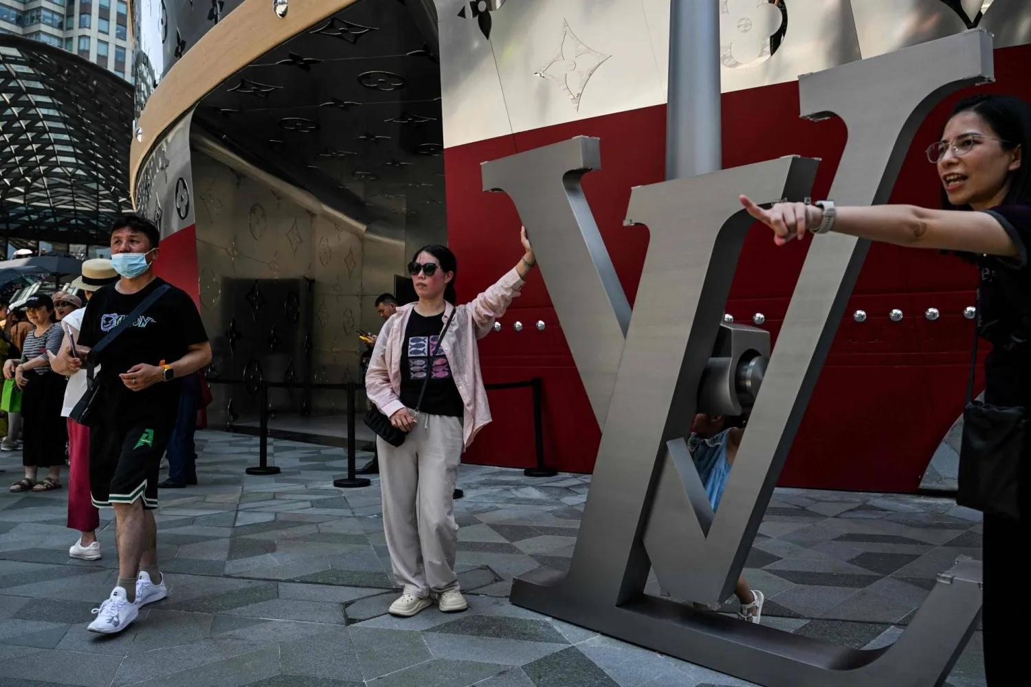 People pose for pictures next to "The Louis", a large ship-shaped structure of the Louis Vuitton brand, in Shanghai on July 15, 2025. (Photo by Hector RETAMAL / AFP)