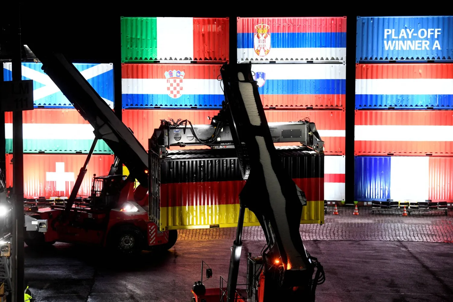 عمال ميناء هامبورغ يكدسون حاويات عليها أعلام فرق «يورو 2024» (رويترز)