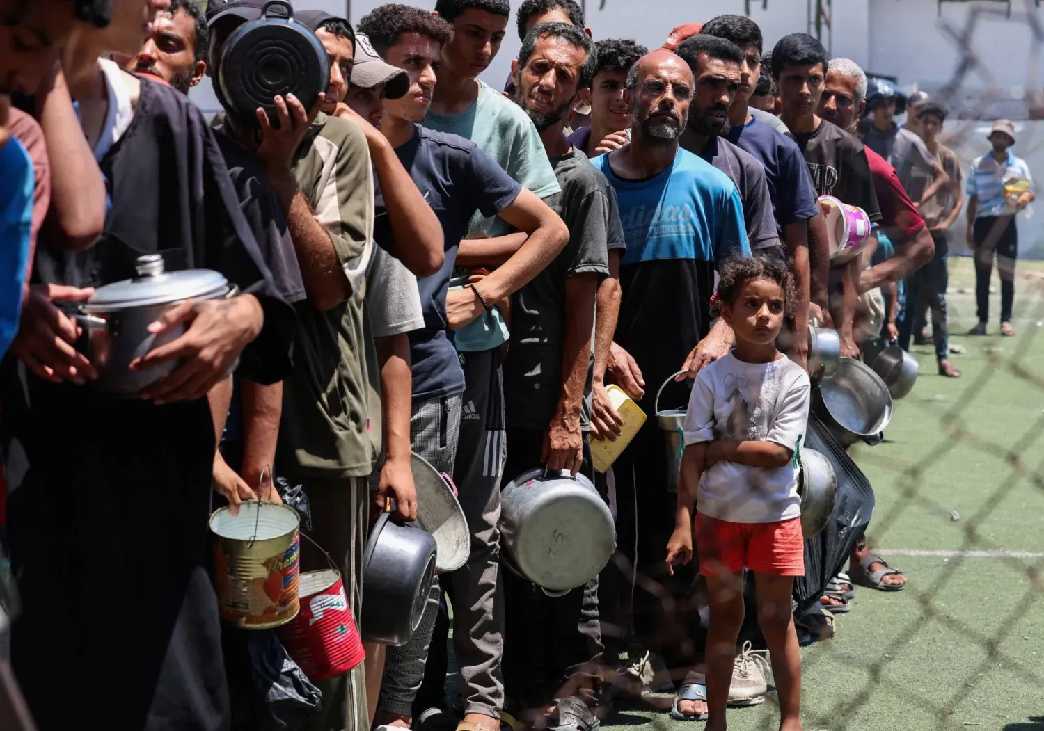Filistinliler Gazze Şeridi'nin orta kesimindeki Nuseyrat'ta açlık krizinin ortasında bir yardım mutfağından yiyecek almak için toplanıyor (Reuters)