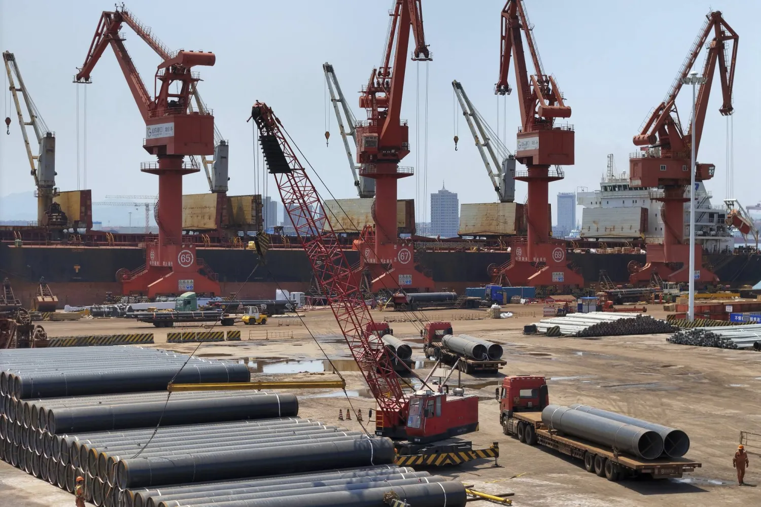 أنابيب من الصلب في انتظار الشحن بميناء لونغكو شرق الصين (أ.ب)