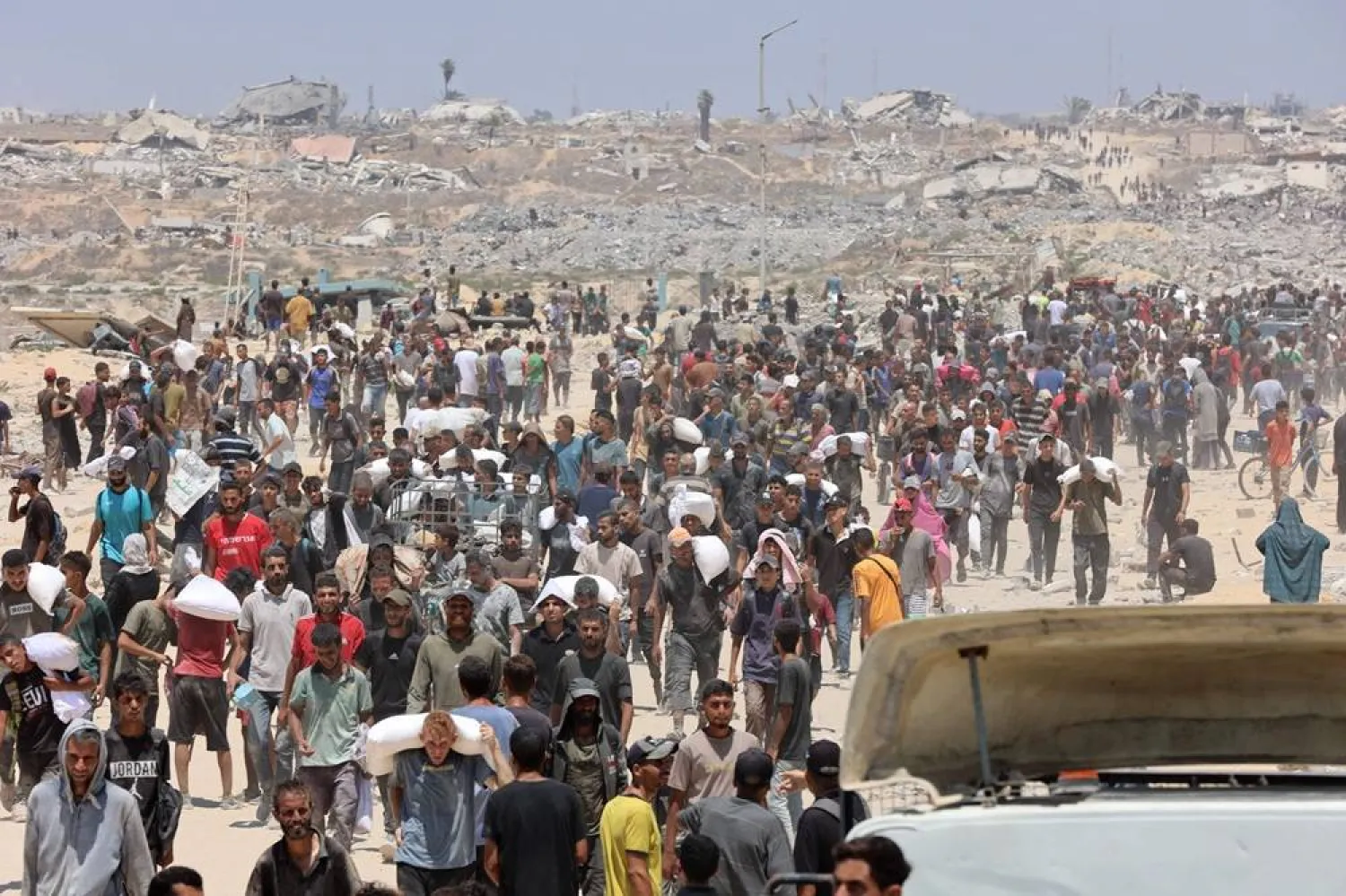 People make their way along al-Rashid street in western Jabalia on July 22, 2025, after receiving humanitarian aid from an aid distribution point in the northern Gaza Strip. (AFP)