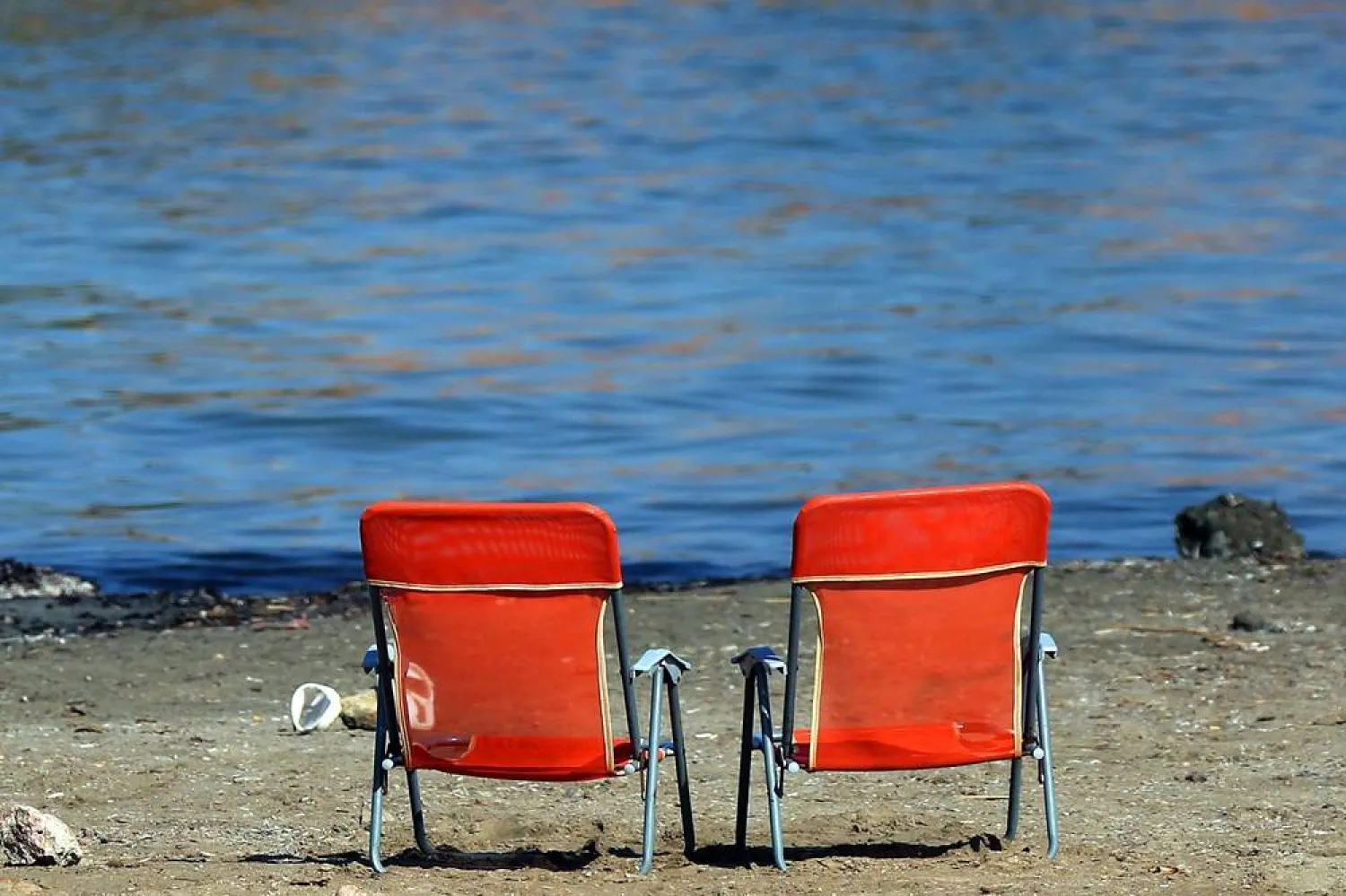 Two empty chairs stand on a beach as people cool off during a heat wave, near Athens, Greece, 22 July 2025. (EPA)