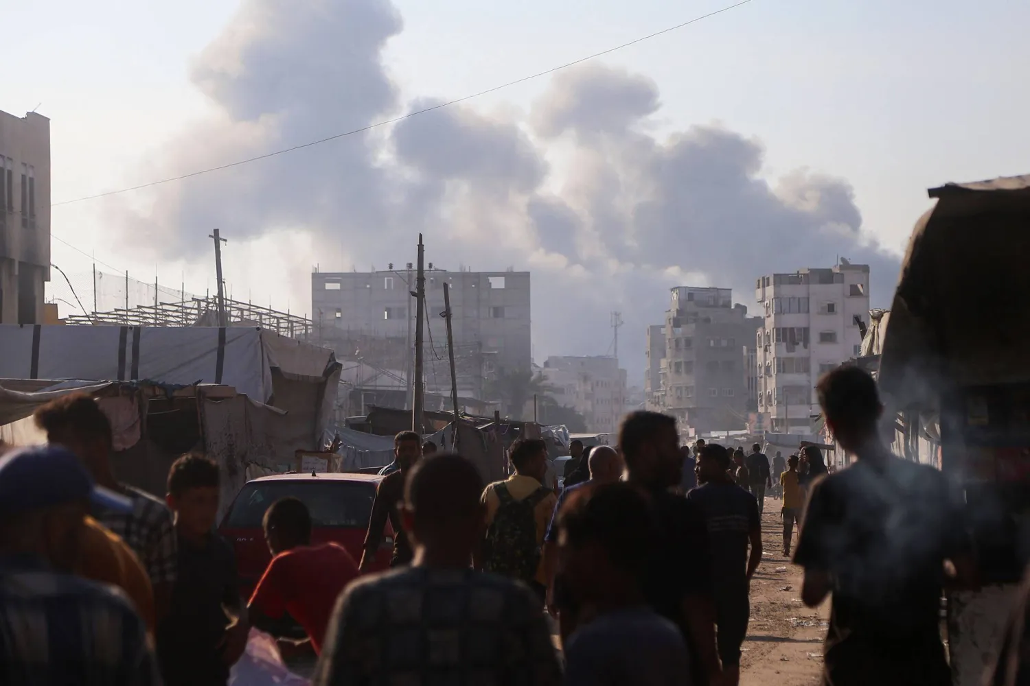 فلسطينيون نازحون ينظرون إلى أعمدة الدخان المتصاعدة وسط الغارات الإسرائيلية على خان يونس في جنوب قطاع غزة (أ.ف.ب)