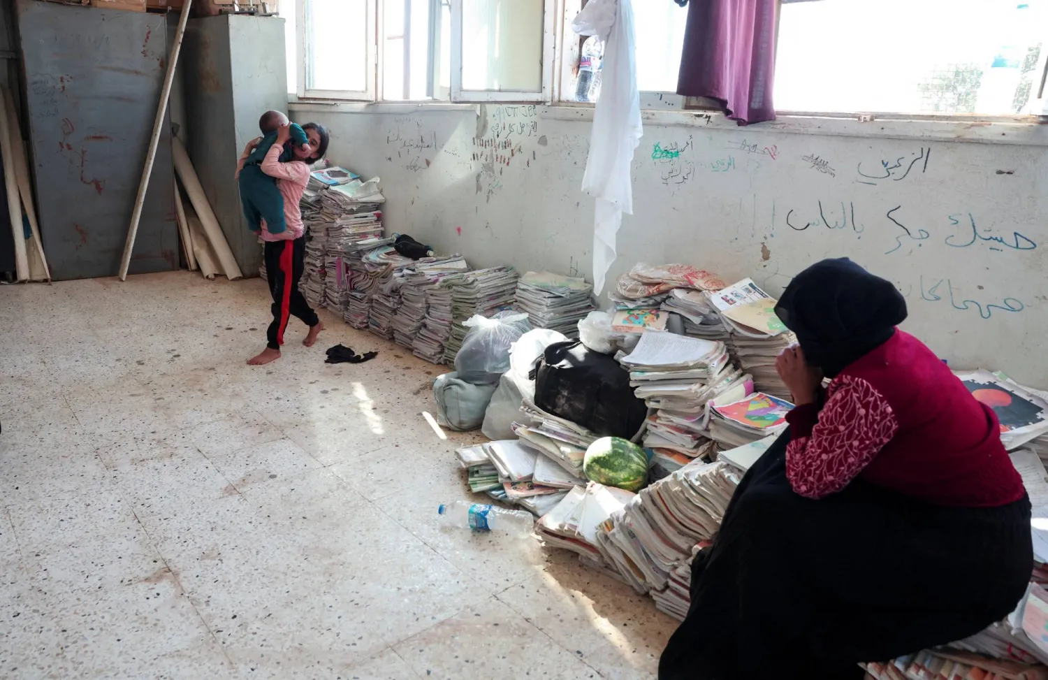 عائلات بدوية غادرت محافظة السويداء في إطار اتفاق بين الحكومة السورية ومسلحين دروز تقيم في مدرسة تُستخدم كمركز إيواء في محافظة درعا جنوب سوريا الثلاثاء (رويترز)