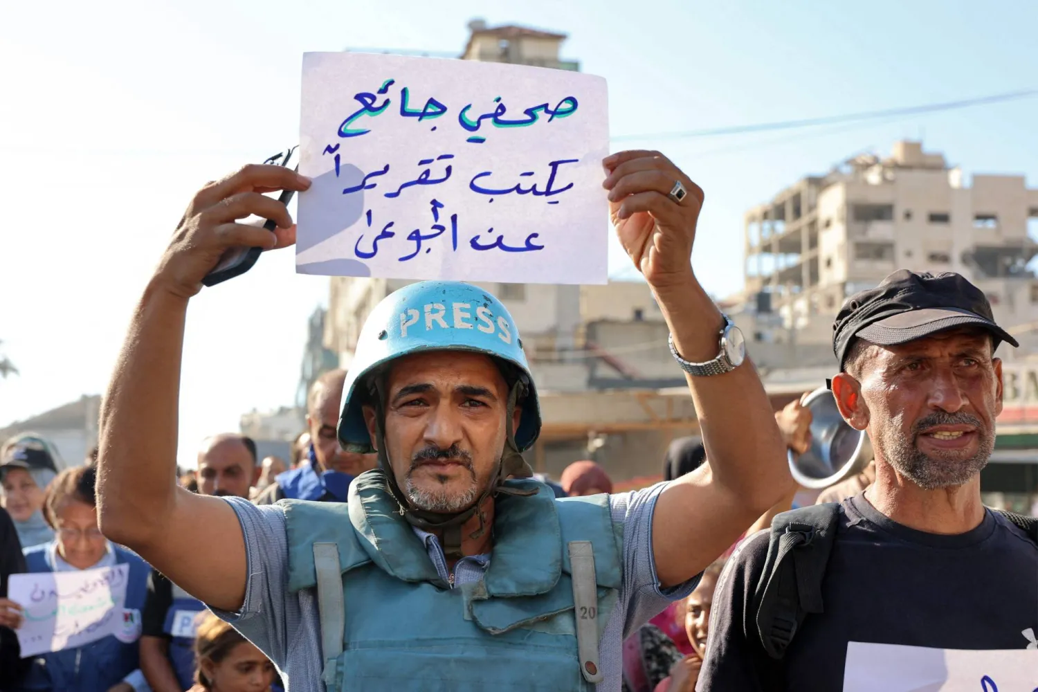 صحفي فلسطيني يحمل لافتة تعبر عن أوضاع غزة المأساوية (أ.ف.ب)