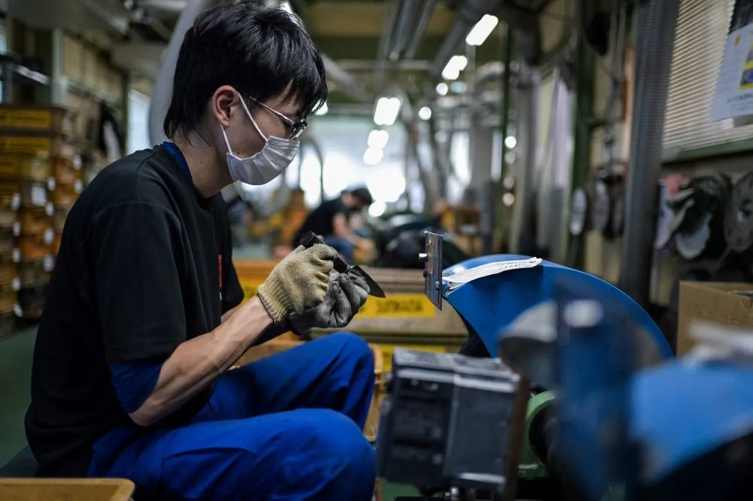 An employee for Japanese knife manufacturer Sumikama Cutlery sharpens blades at their factory in Seki, Gifu prefecture, north of Nagoya, on July 22, 2025. (AFP)