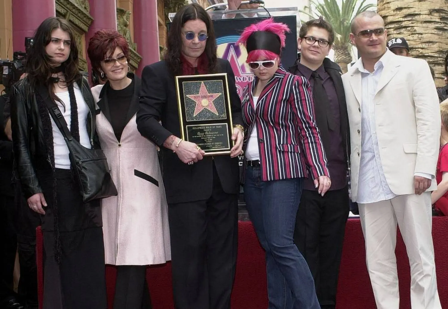 Metal-rock star Ozzy Osbourne holds a replica of his new star on the Hollywood Walk of Fame as he poses with his family during a ceremony on April 12, 2002, in Los Angeles. Pictured with Osbourne, from left, are Aimee, Sharon, Kelly, Jack and Louis. (AP Photo/Nick Ut, File)