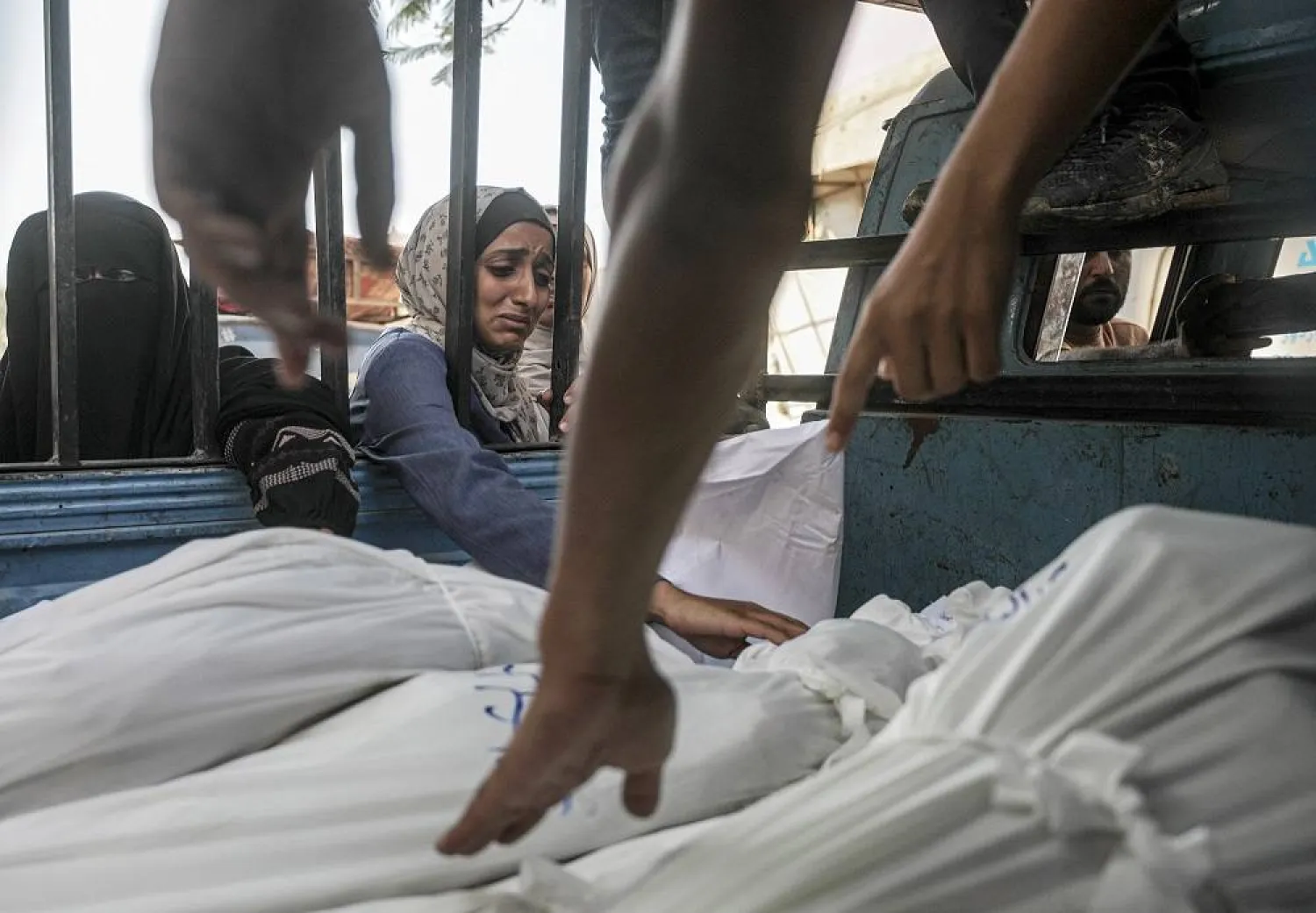 A woman mourns over shrouded bodies of Mushtaha family members at the Al-Shifa in Gaza City, 23 July 2025. (EPA)