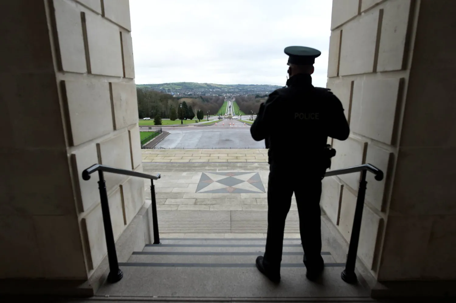 شرطي يقف على درجات برلمان ستورمونت في بلفاست بآيرلندا الشمالية (رويترز)