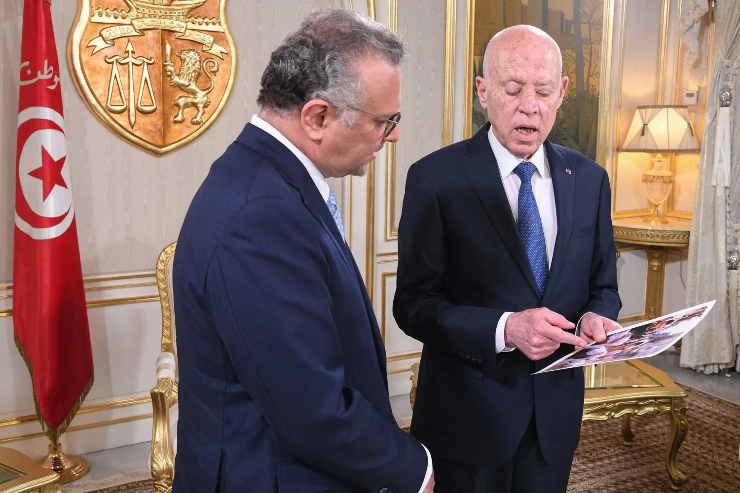 تُظهر هذه الصورة المنشورة التي قدمتها دائرة الصحافة التابعة للرئاسة التونسية الرئيس التونسي وهو يُظهر لمسعد بولس صوراً لأطفال يتضورون جوعاً (أ.ف.ب)