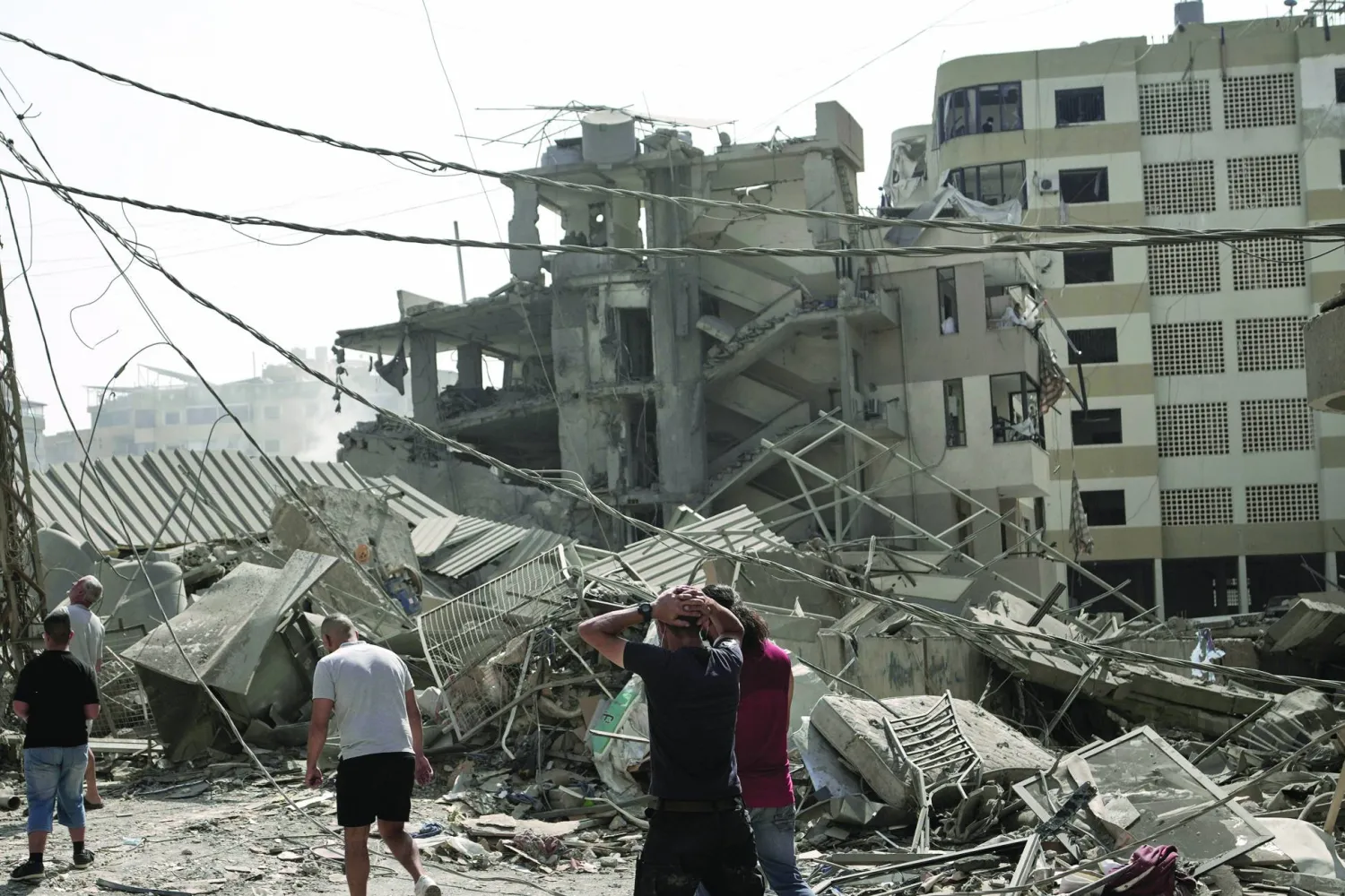 لبنانيون يتفقدون الدمار الناتج عن قصف إسرائيلي استهدف الضاحية الجنوبية الشهر الماضي (أ.ب)