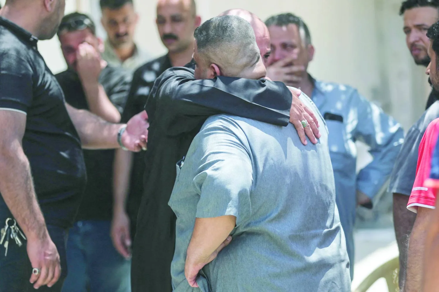 أقارب ضحايا حريق المركز التجاري في الكوت يحتضن بعضهم بعضاً خارج قسم الطب الشرعي بالمدينة (أ.ف.ب)