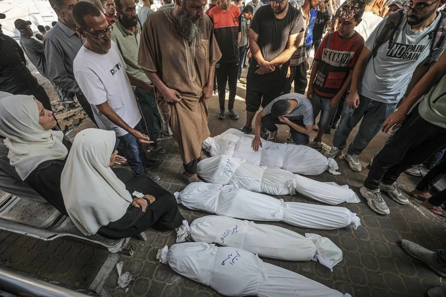 Relatives mourn over the shrouded bodies of Al-Shaer family members at the Al-Shifa in Gaza City, 23 July 2025. (EPA) 
