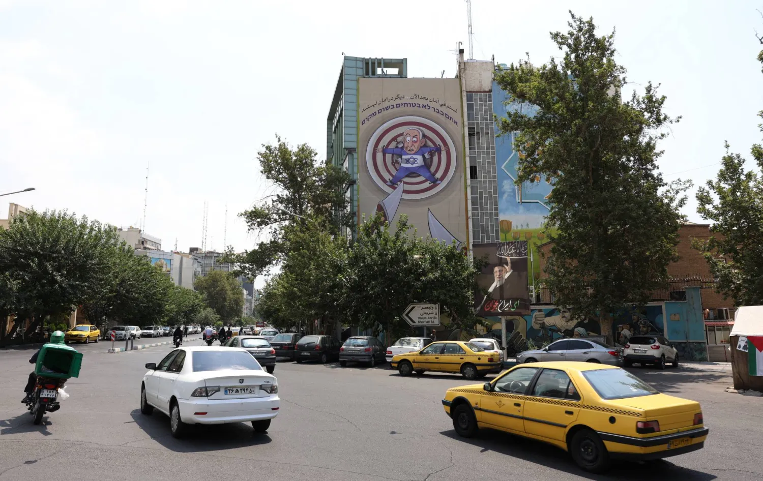 لافتة دعائية معلّقة على مبنى التنسيق الإيراني الفلسطيني وسط طهران وتُظهر كاريكاتيراً مناهضاً لإسرائيل يَسخر من رئيس الوزراء بنيامين نتنياهو (إ.ب.أ)