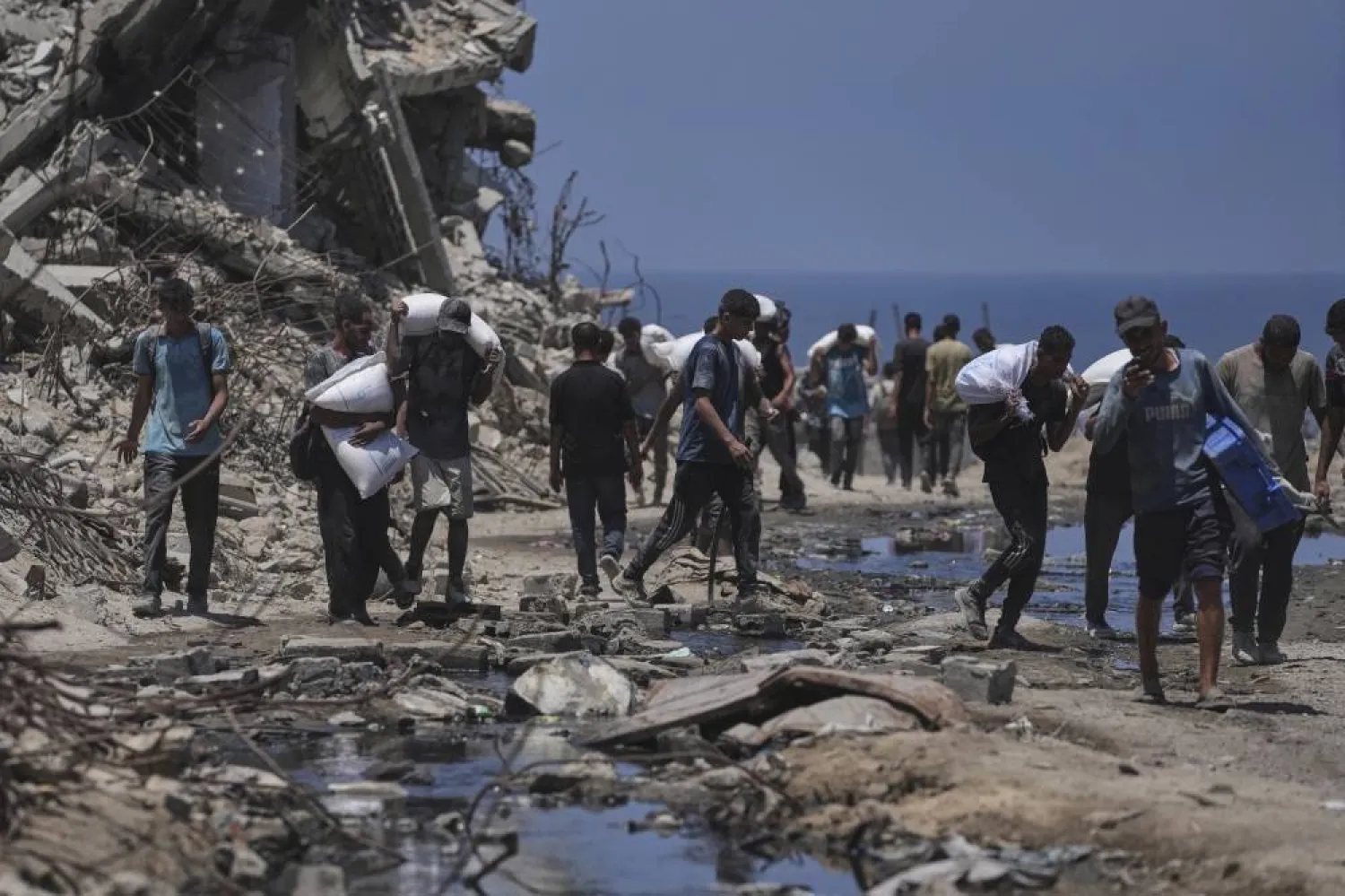 غزيون يحملون ما تيسر من مساعدات غذائية (رويترز)