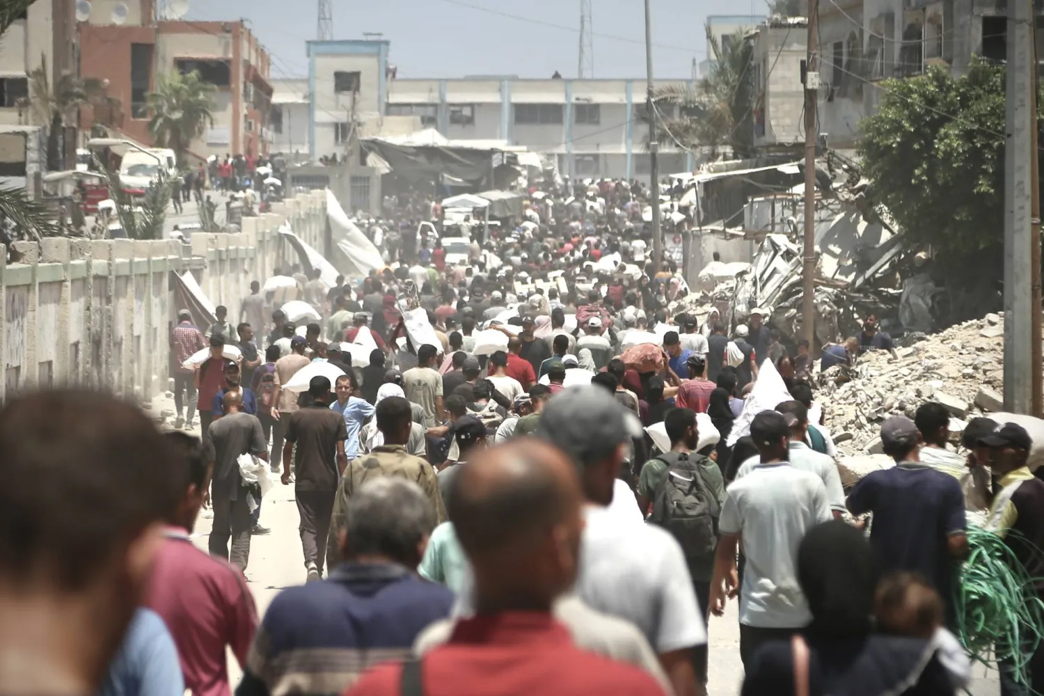 23 July 2025, Palestinian Territories, Khan Younis: Palestinians walk carrying sacks of flour that were taken from a raided truck carrying foodstuffs, in Khan Yunis in the southern Gaza Strip. Photo: Abdallah Alattar/APA Images via ZUMA Press Wire/dpa