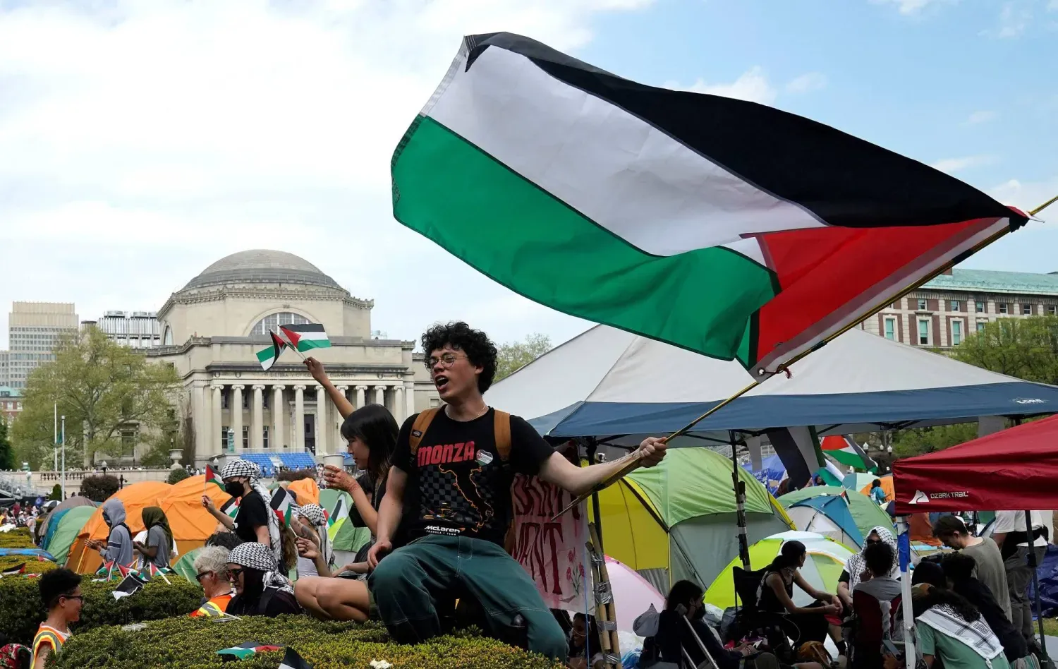 Protestocular, Columbia Üniversitesi'nin batı bahçesinde Filistin bayrakları sallıyor (AFP)