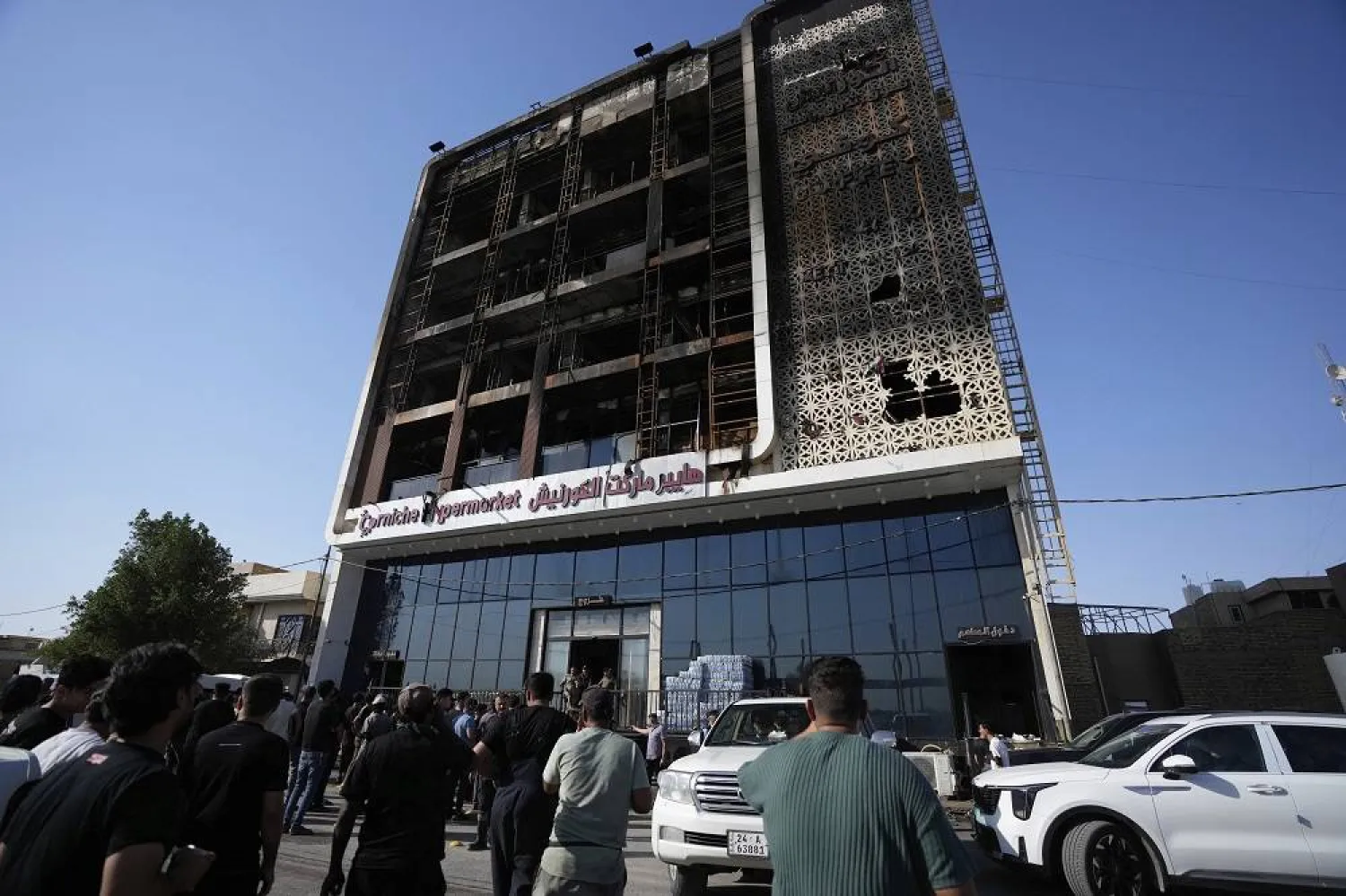 Iraqi people gather in front of a burning hypermarket building in Kut, Iraq, Thursday, July 17, 2025. (AP)