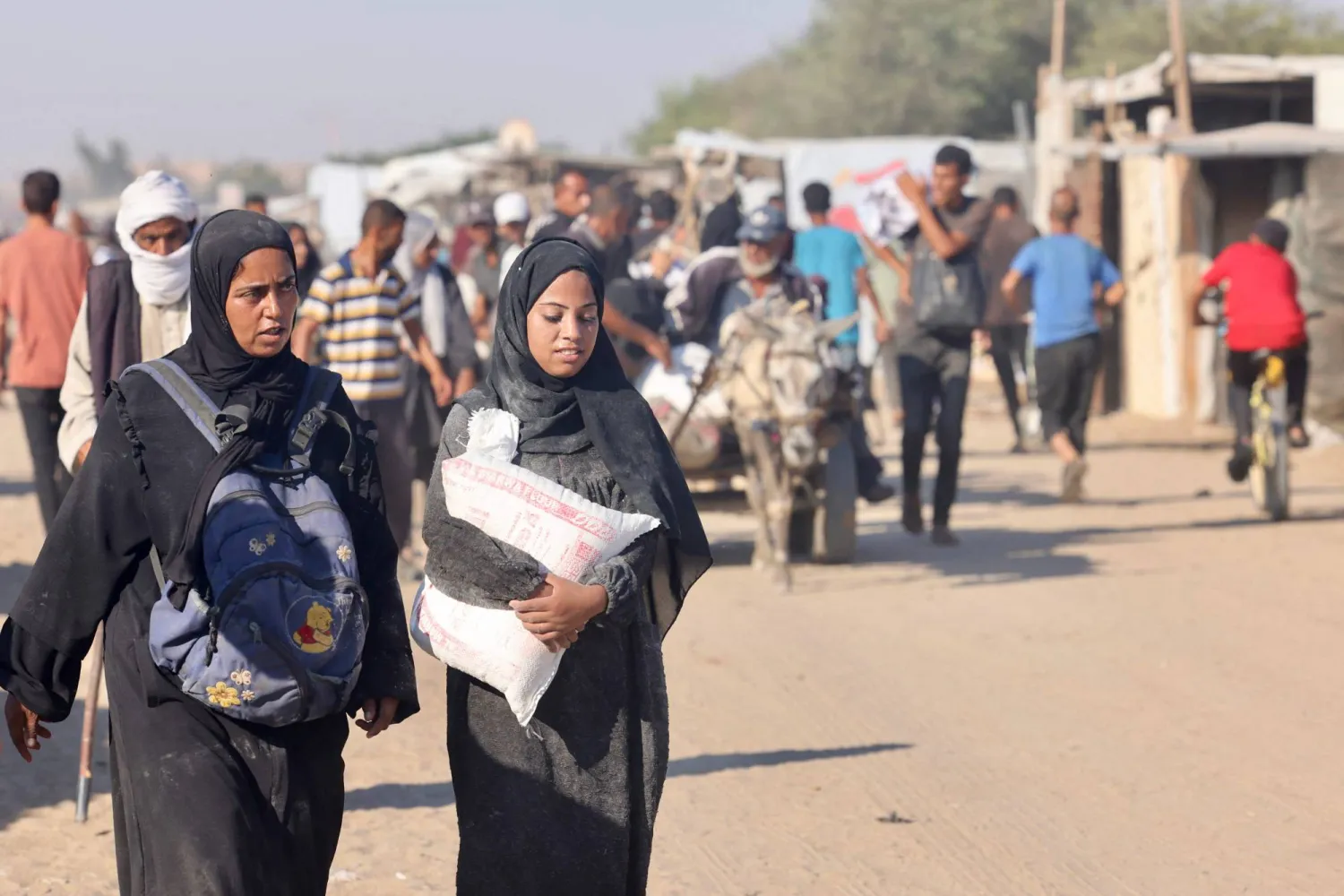 Palestinians make their way along al-Rashid street in western Jabalia on July 24, 2025, after receiving humanitarian aid from an aid distribution point in the northern Gaza Strip. (Photo by Eyad BABA / AFP)