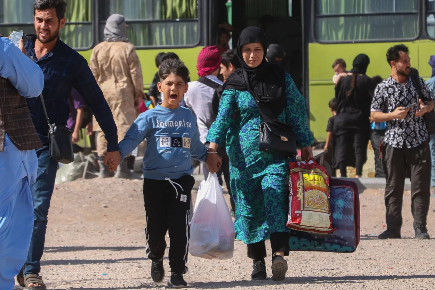 حافلة إيرانية تُنزل لاجئين أفغان عند نقطة الصفر على حدود إسلام قلعة في ولاية هرات الخميس (أ.ف.ب)