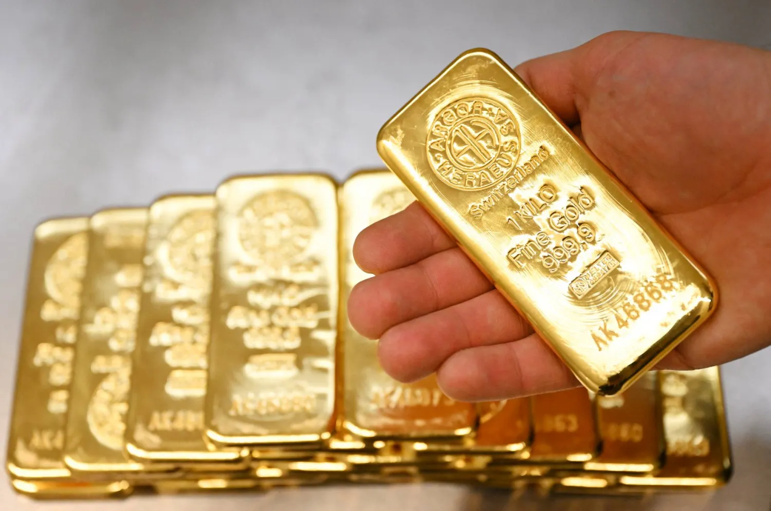 رجل يمسك بسبيكة ذهب في معرض بمدينة ميونيخ الألمانية (رويترز)