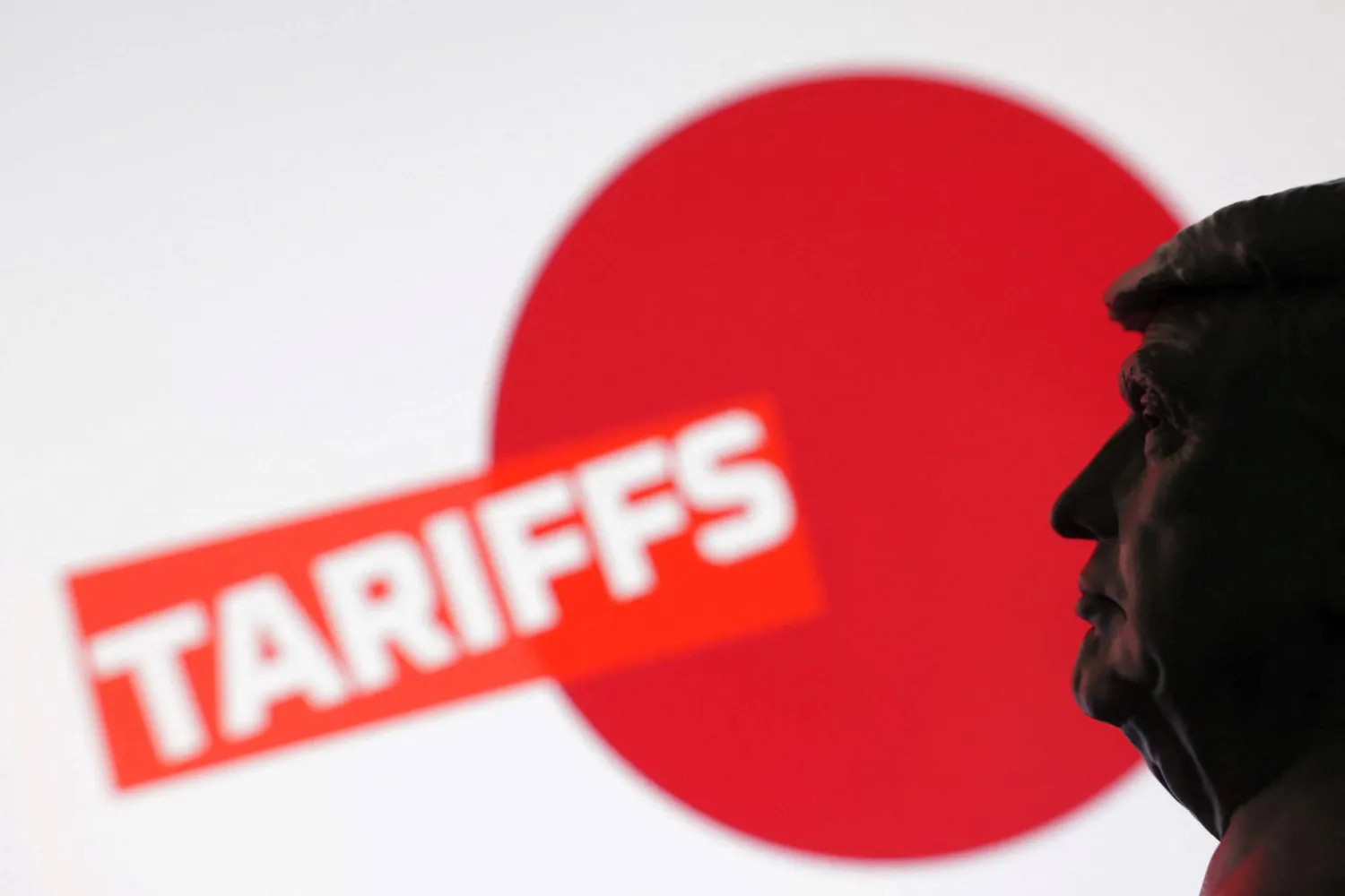 ظل الرئيس الأميركي دونالد ترمب وفي الخلفية علم اليابان وكلمة «تعريفات» (رويترز)