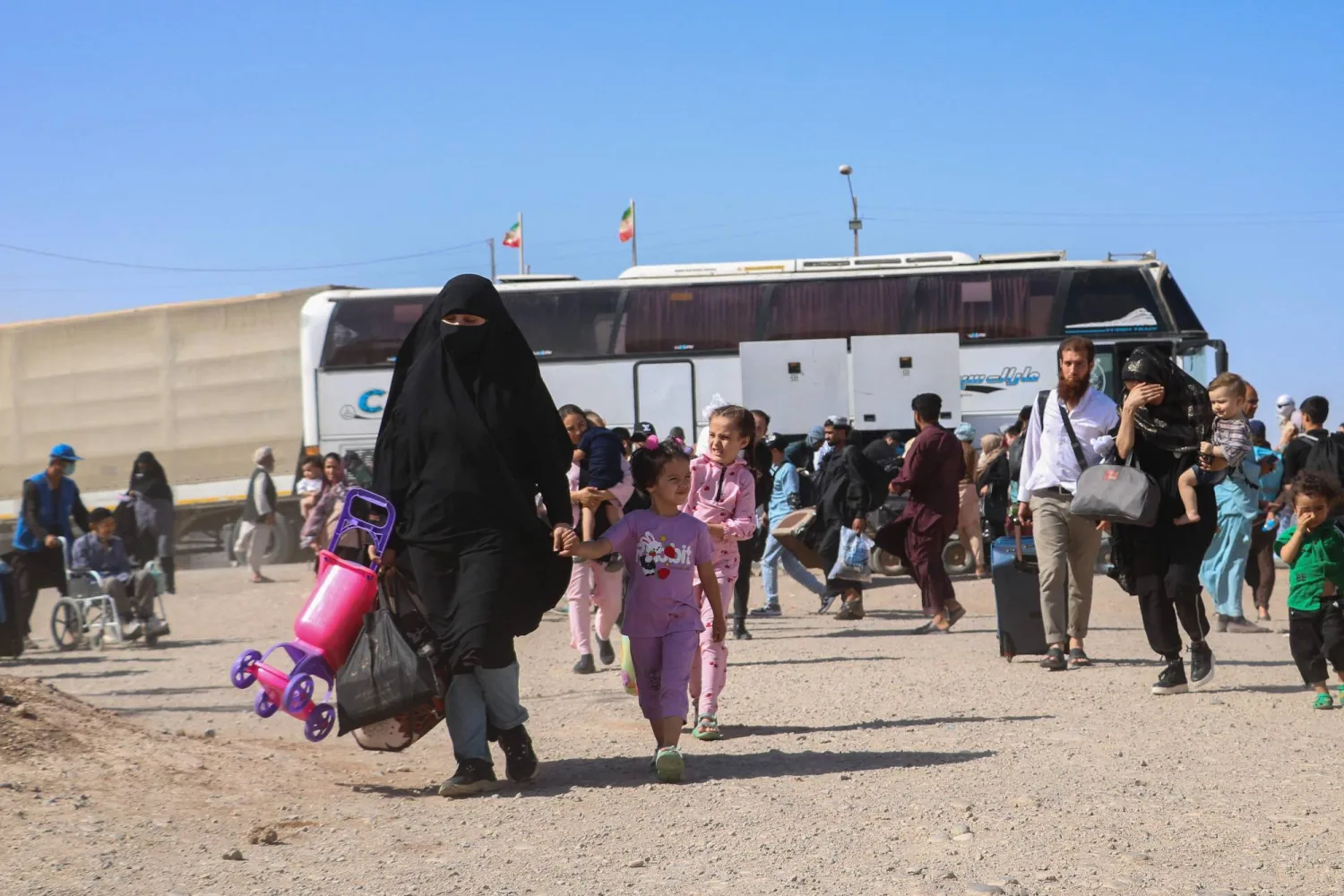 حافلة إيرانية تُنزل لاجئين أفغاناً عند نقطة الصفر على حدود إسلام قلعة في ولاية هرات 24 يوليو 2025 (أ.ف.ب)