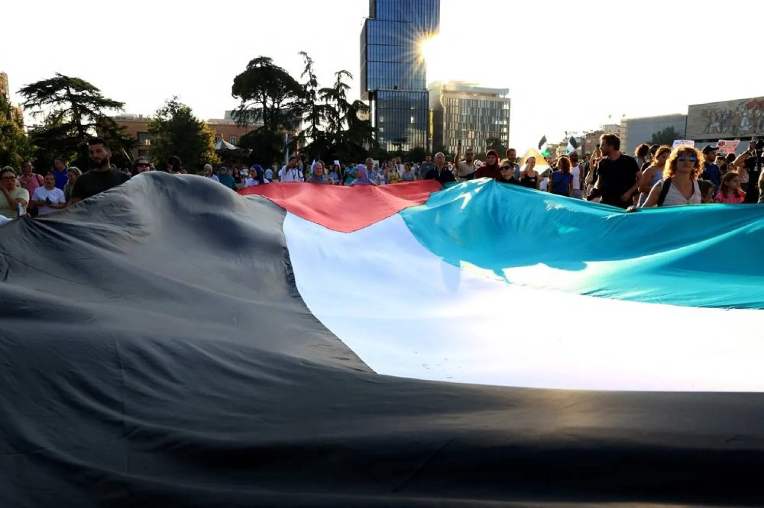 People wave a giant Palestinian flag during a demonstration to support the population of Gaza called by various Albanian social organizations at Skanderbeg square in Tirana, on July 23, 2025. (AFP)